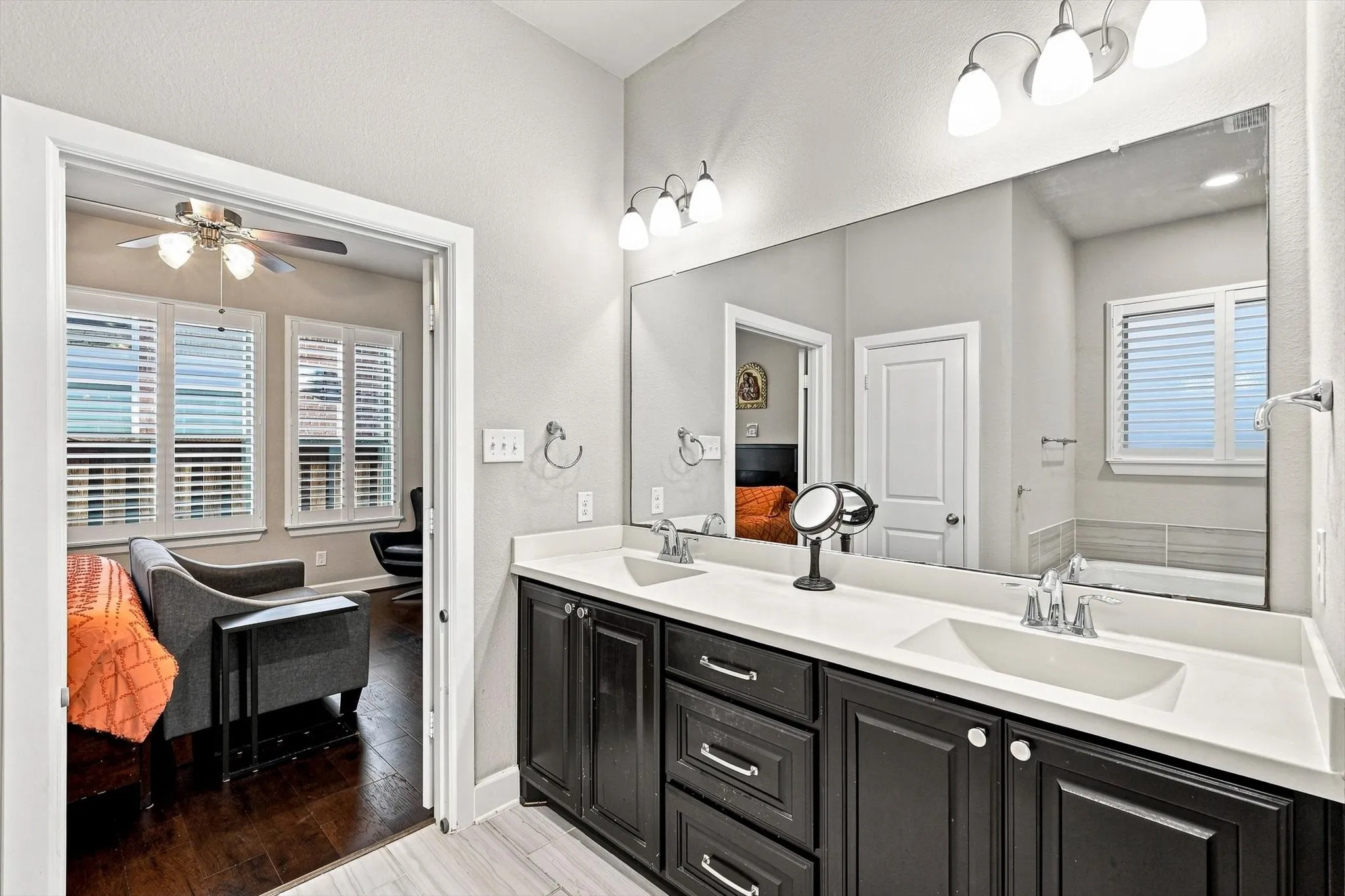 Dual vanity with white countertops, dark wood-finish cabinetry, and built-in mirror