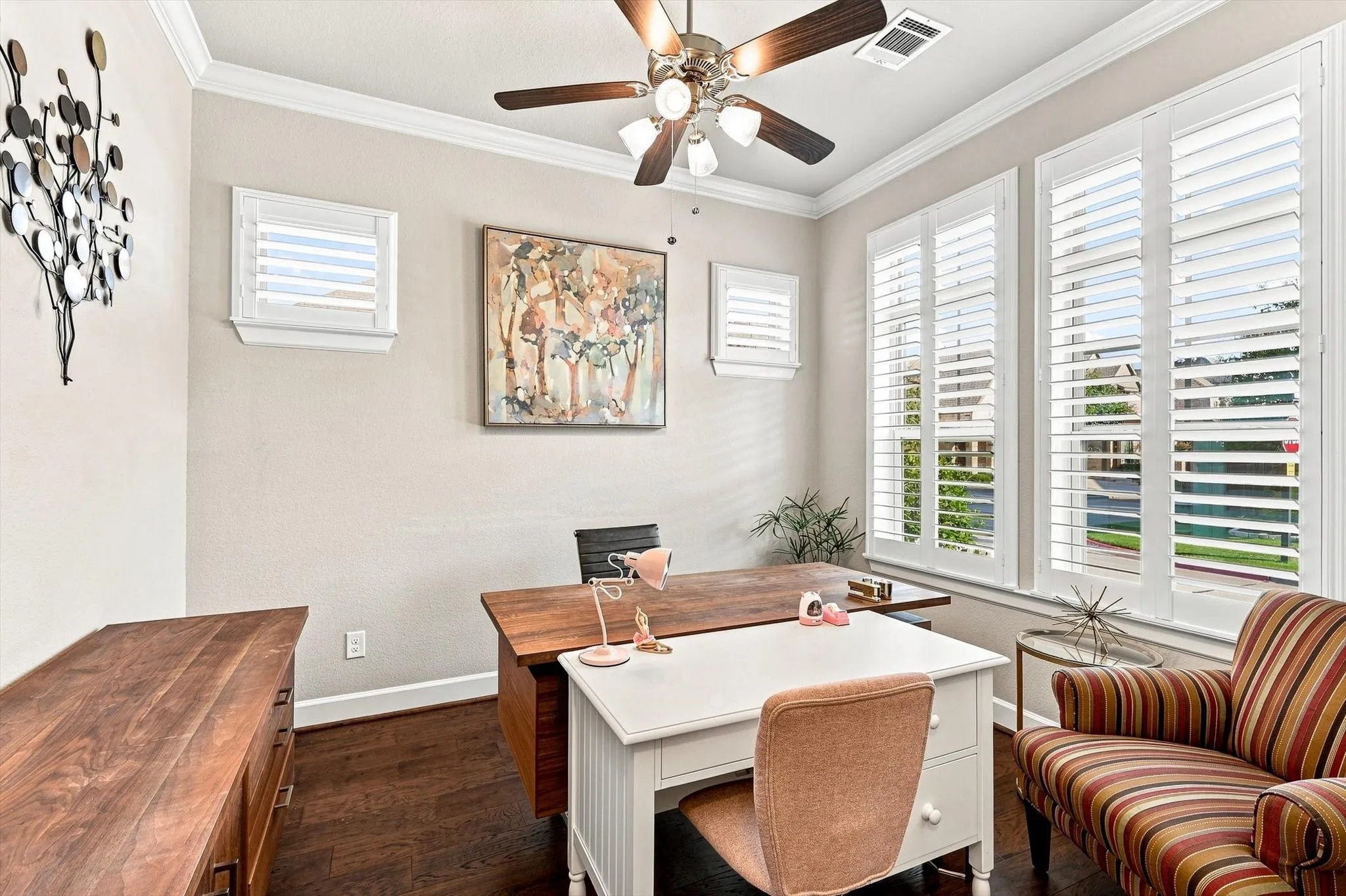 Dark wood-finish flooring, crown molding, and multiple windows with plantation shutters