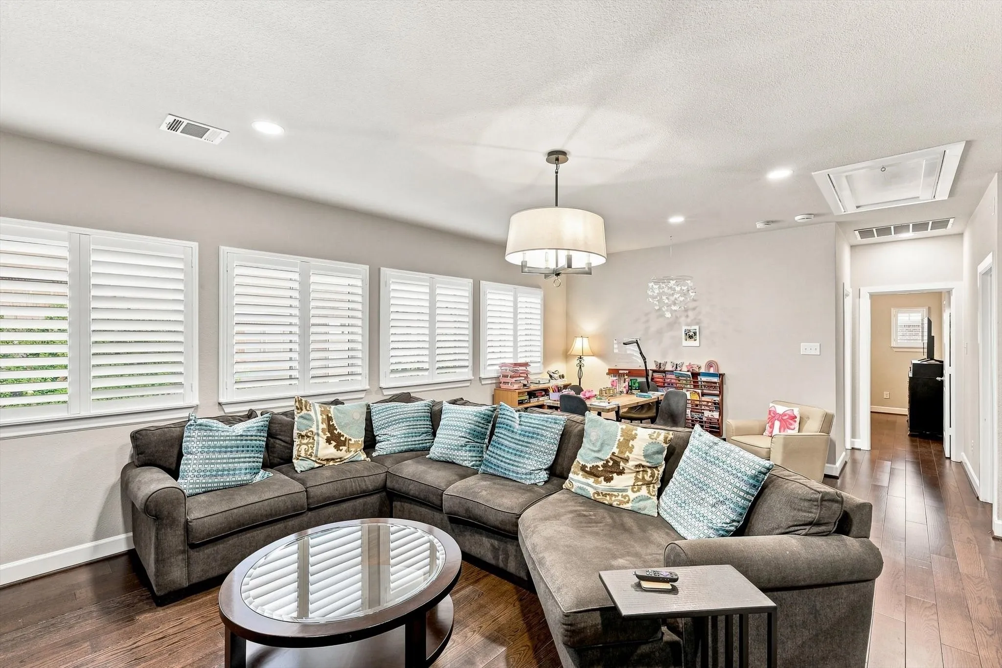 Expansive room with dark wood-finish flooring, recessed lighting, and a drum pendant light fixture