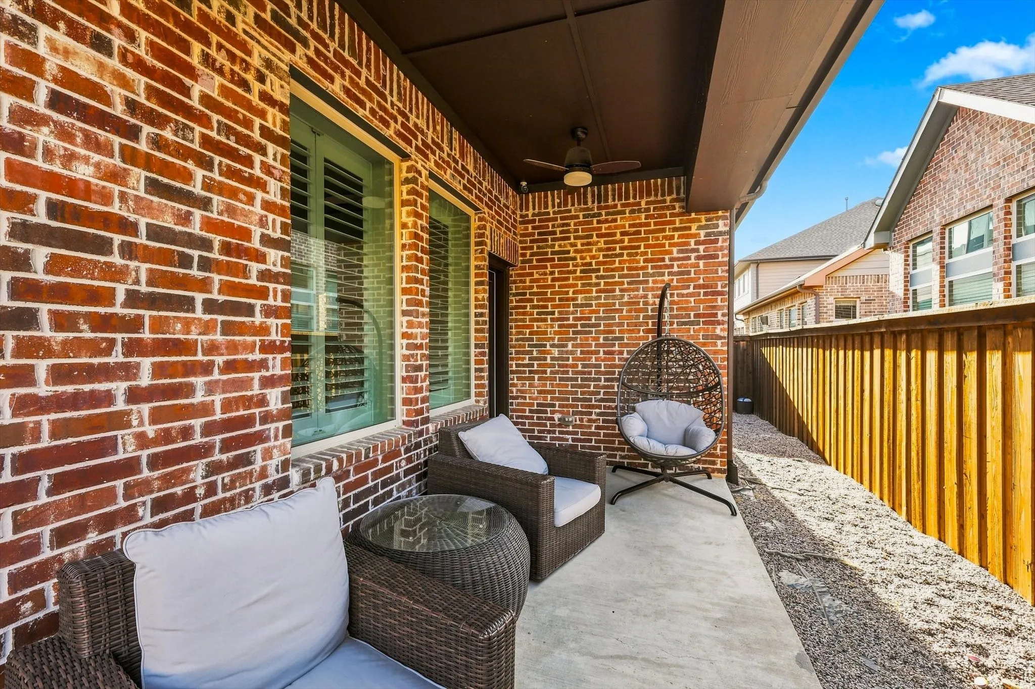 Covered patio featuring a brick exterior wall, concrete flooring, and a ceiling fan