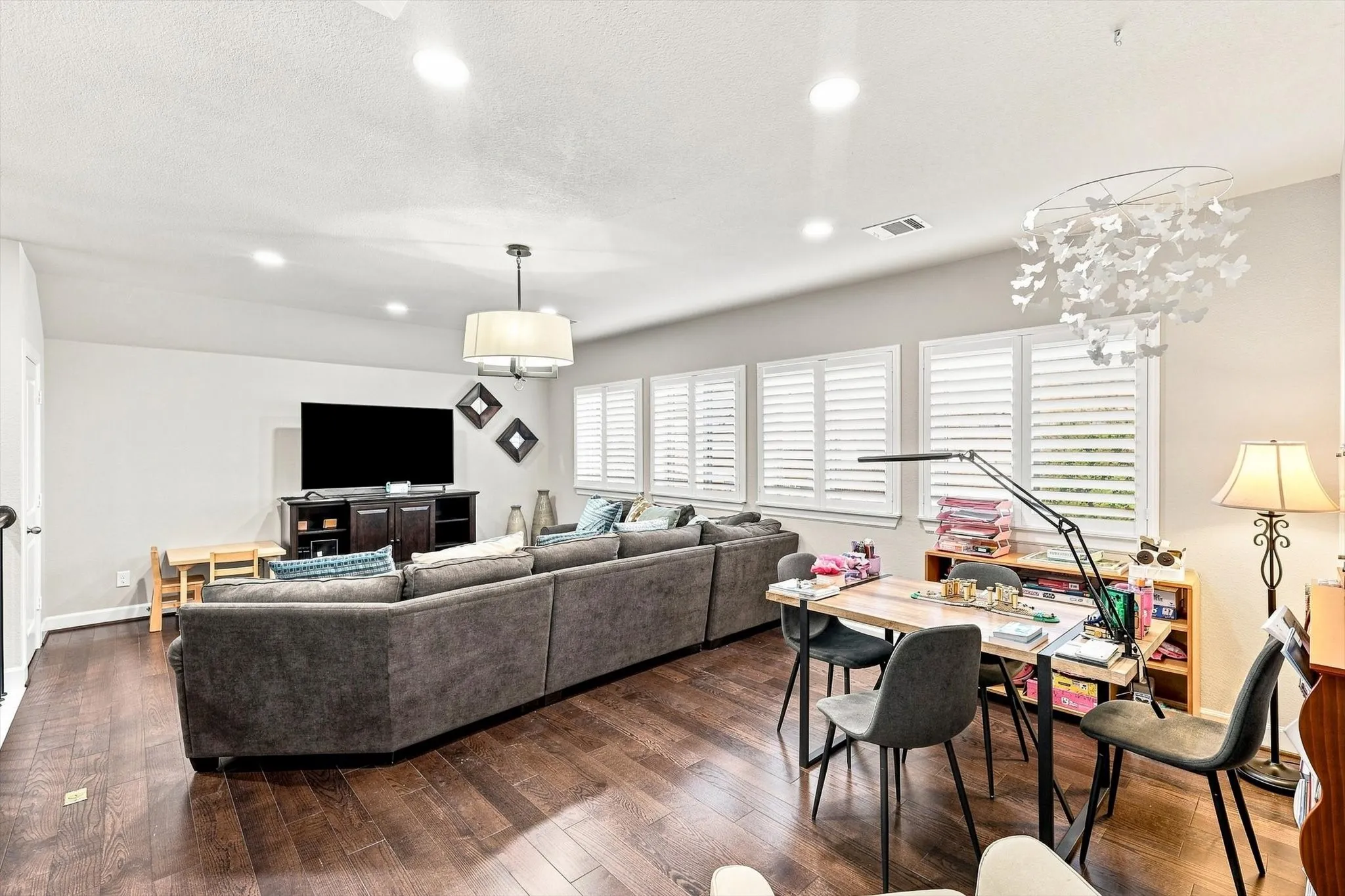 Spacious interior with wood-finish flooring, recessed lighting, and multiple windows featuring plantation shutters