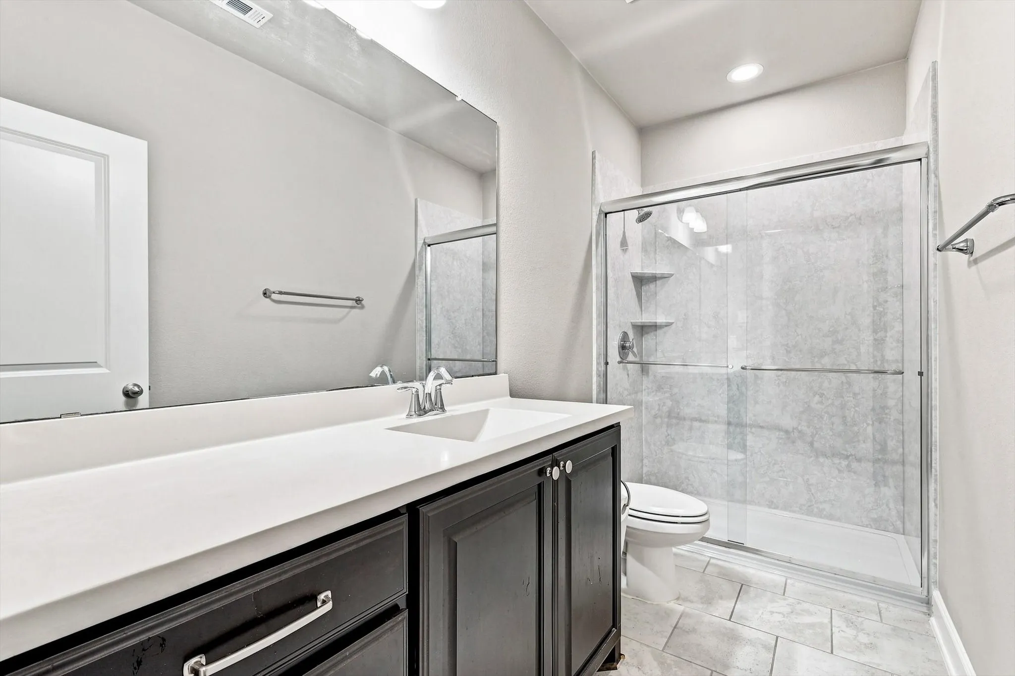 Spacious vanity with an integrated sink, dark wood-finish cabinetry, and a large mirror