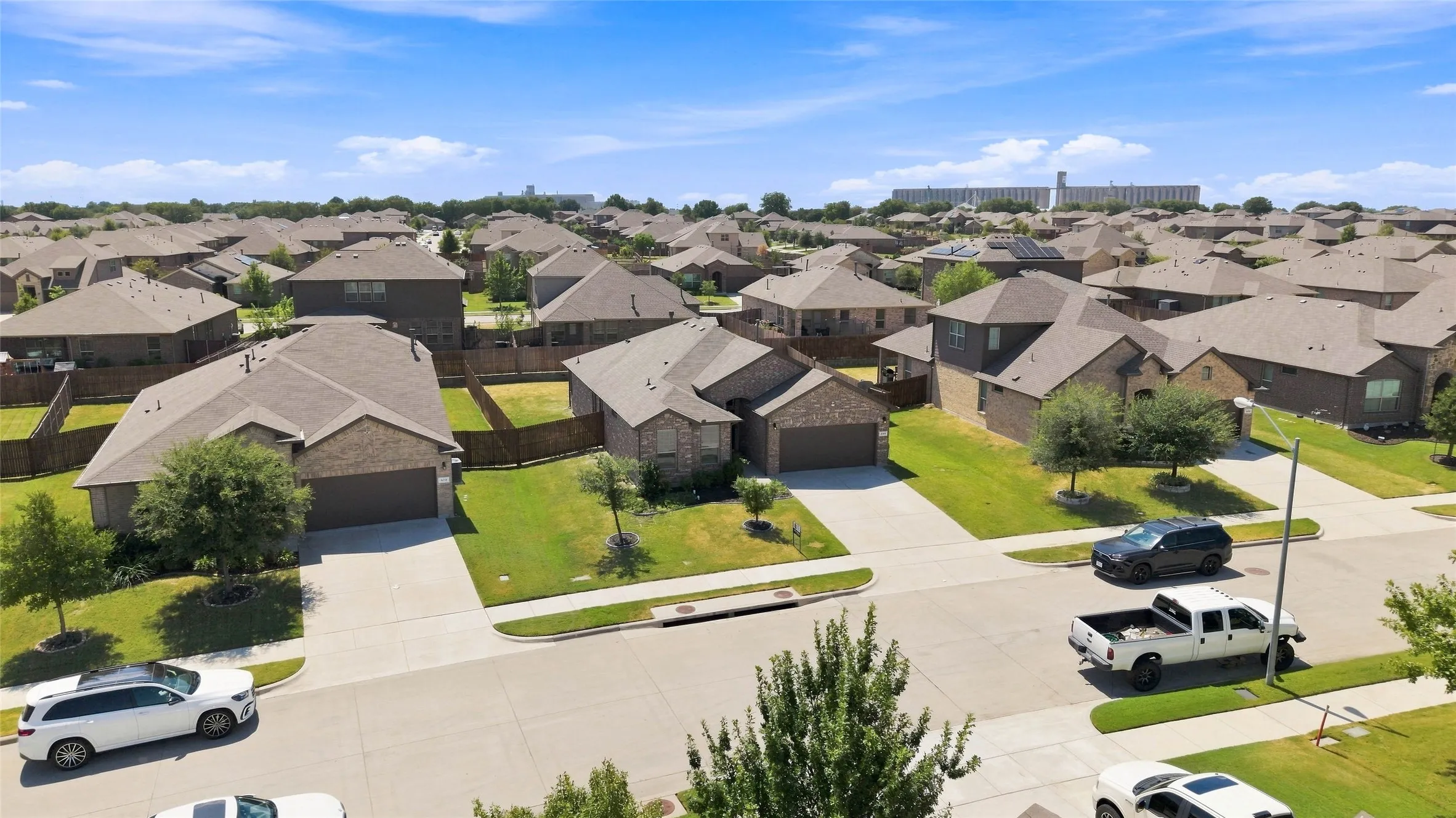 Residential neighborhood featuring single-story and two-story homes, concrete driveways, and manicured lawns