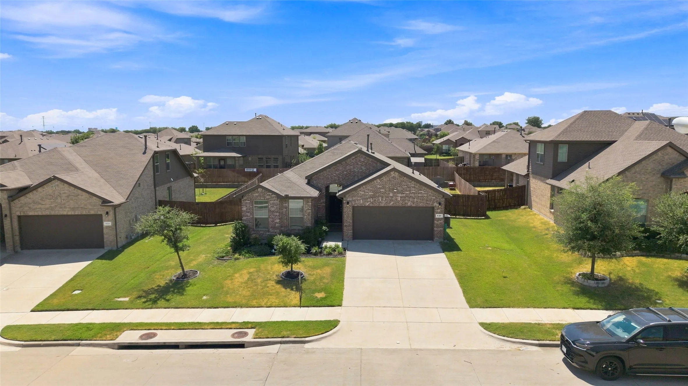 Brick veneer exterior with an attached two-car garage, concrete driveway, and front lawn