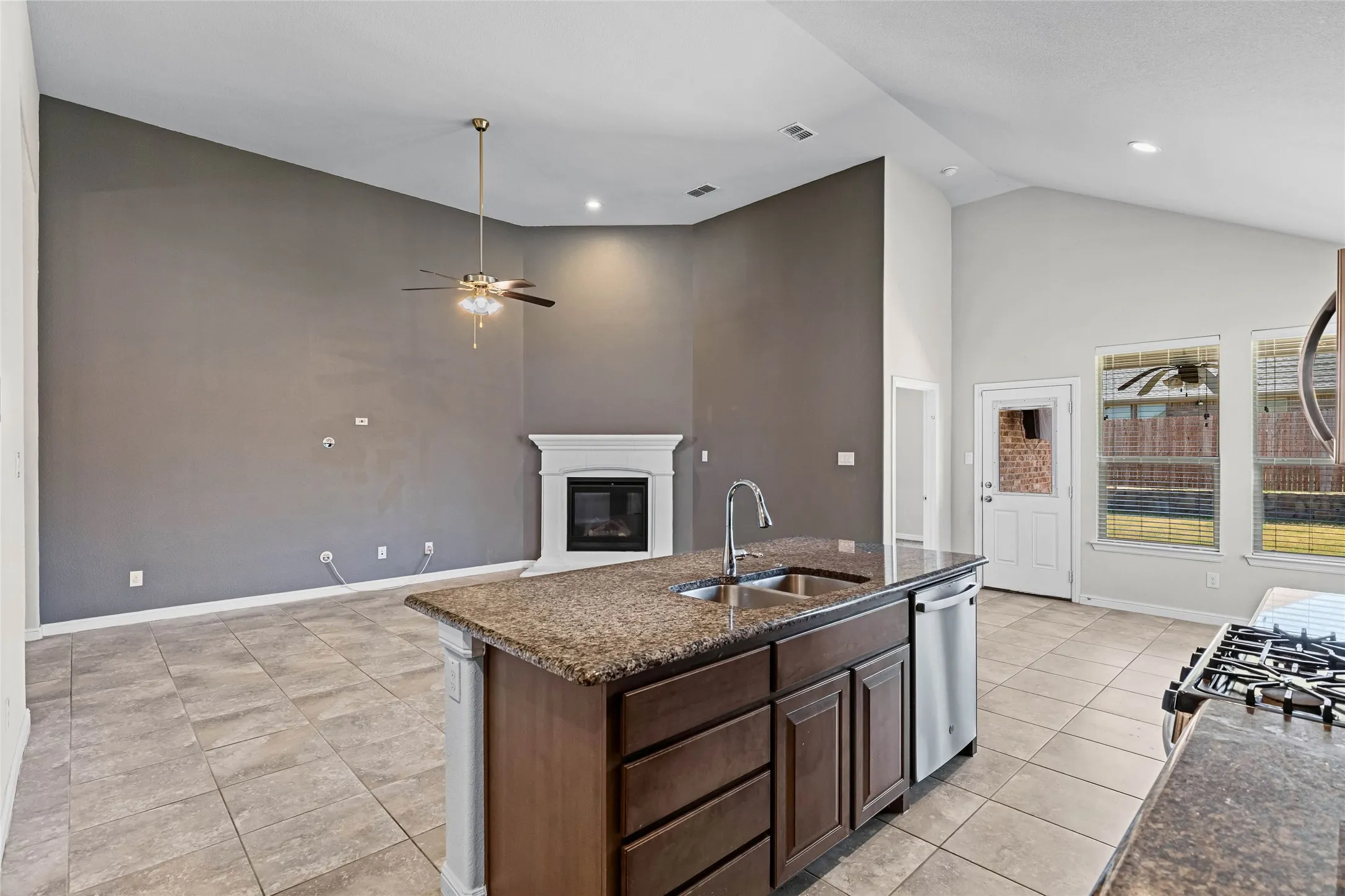 Gourmet kitchen island featuring wood cabinetry, stainless steel sink with professional faucet, and granite countertop