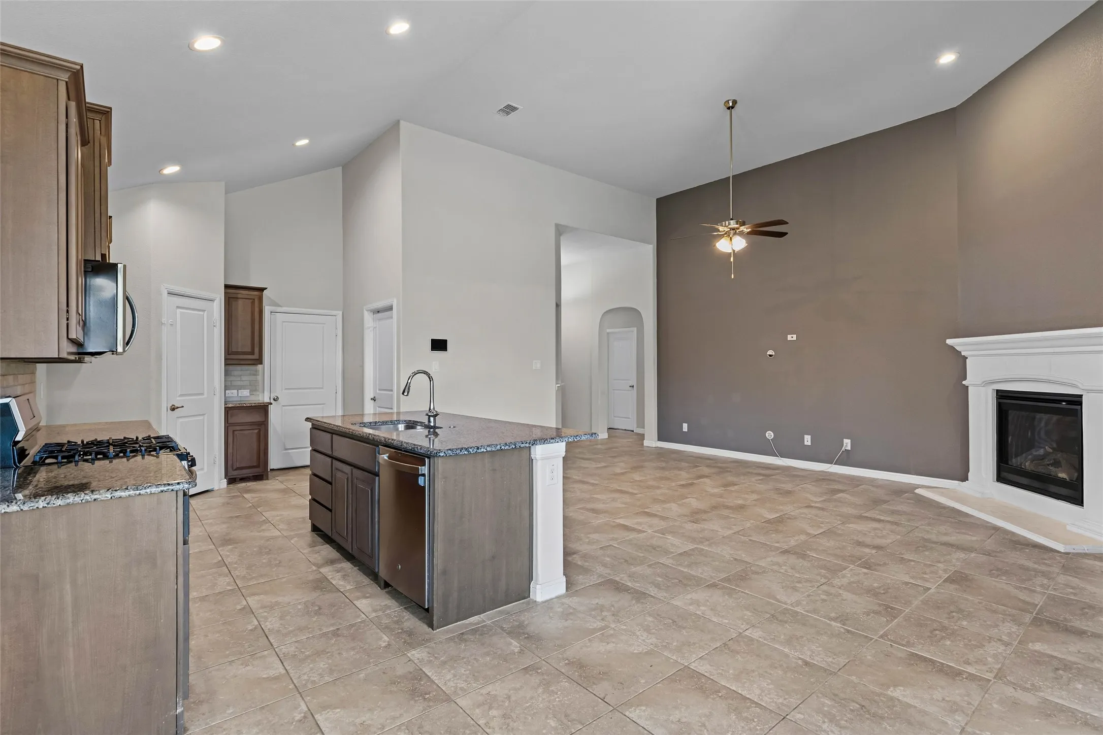 Kitchen island with integrated sink, stainless steel appliances, and granite-finish countertops