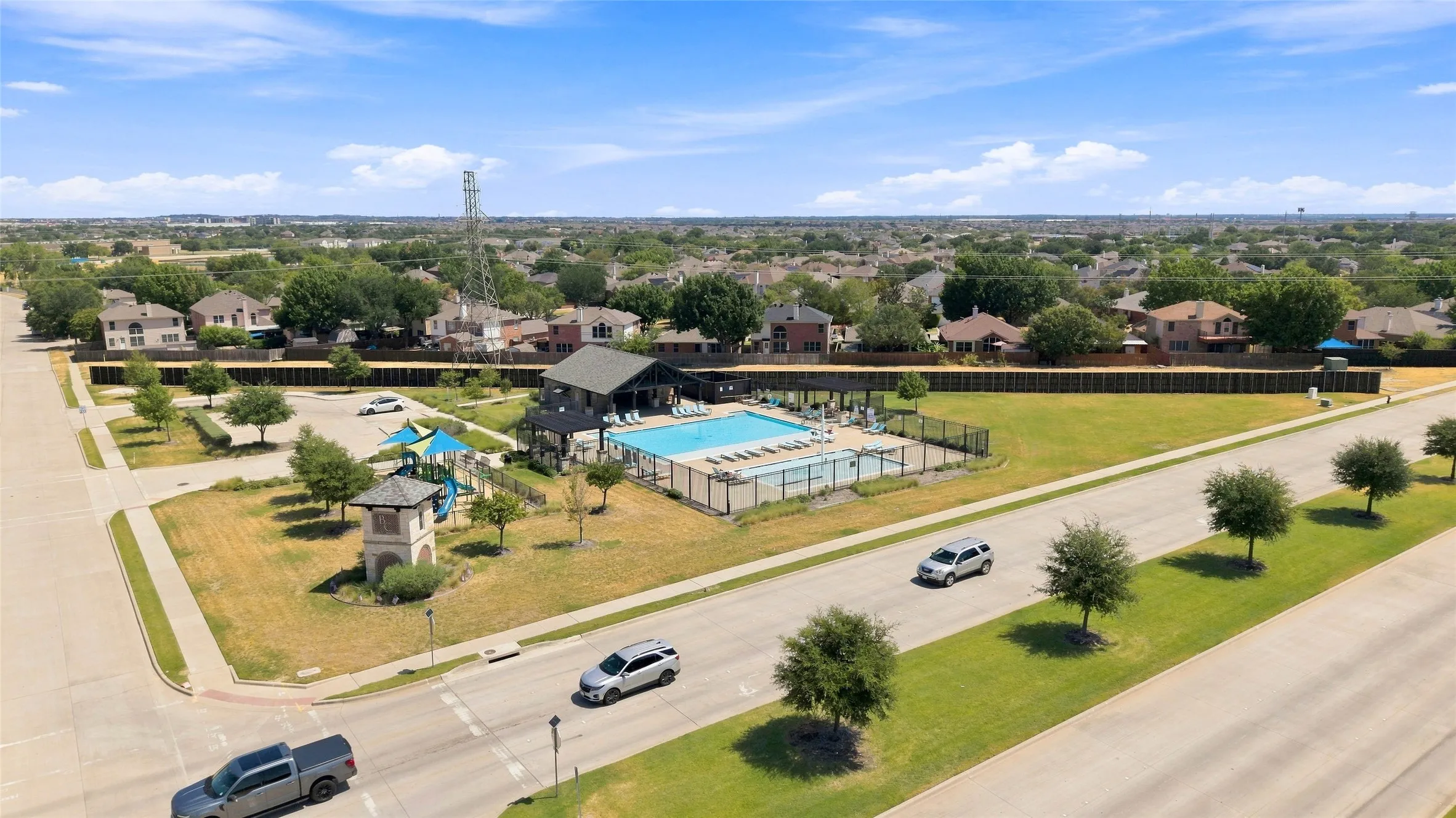 Community swimming pool with surrounding fencing, adjacent recreation structure, and integrated playground equipment