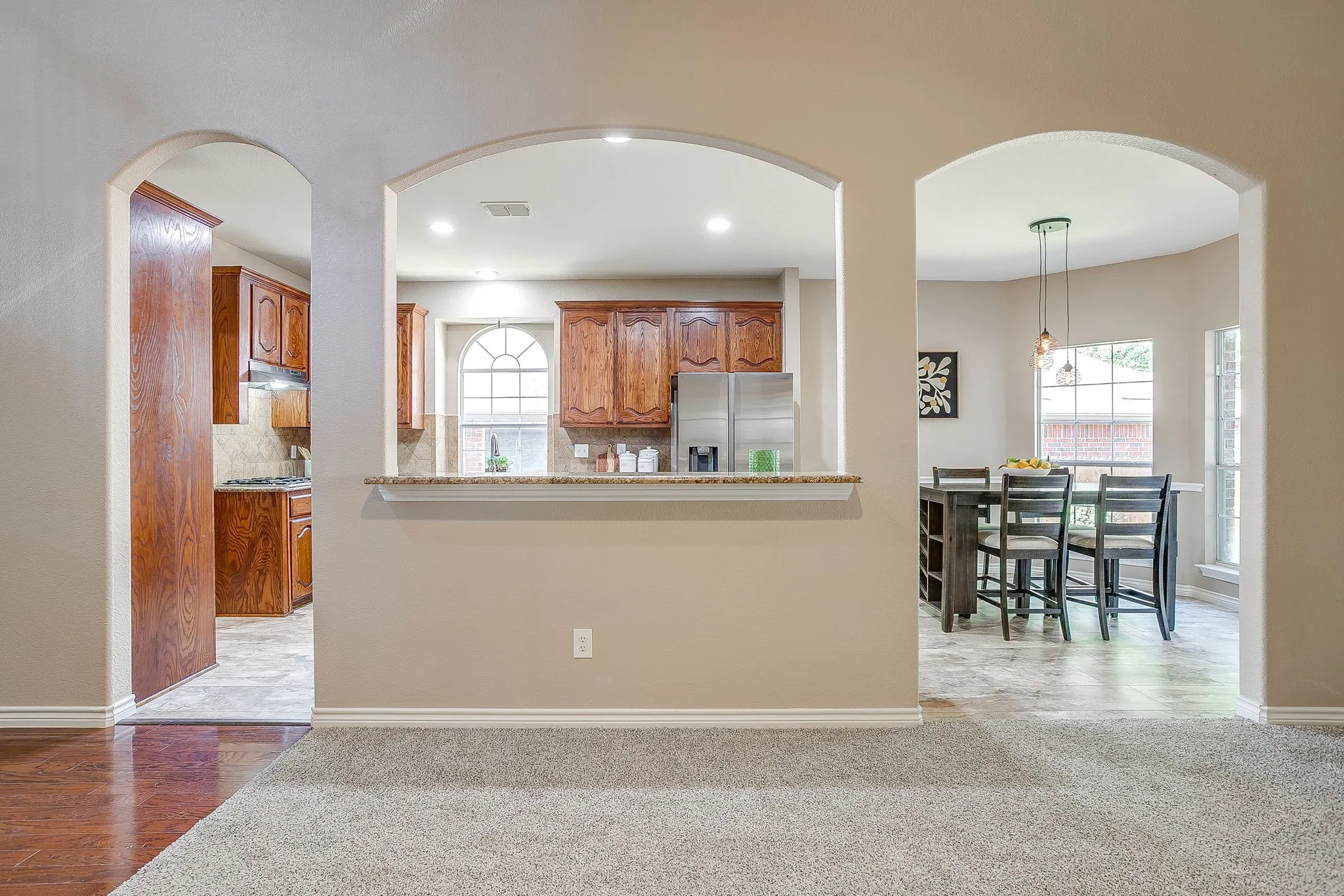 Multiple arched doorways, recessed lighting, wood-finish flooring, and neutral paint colors