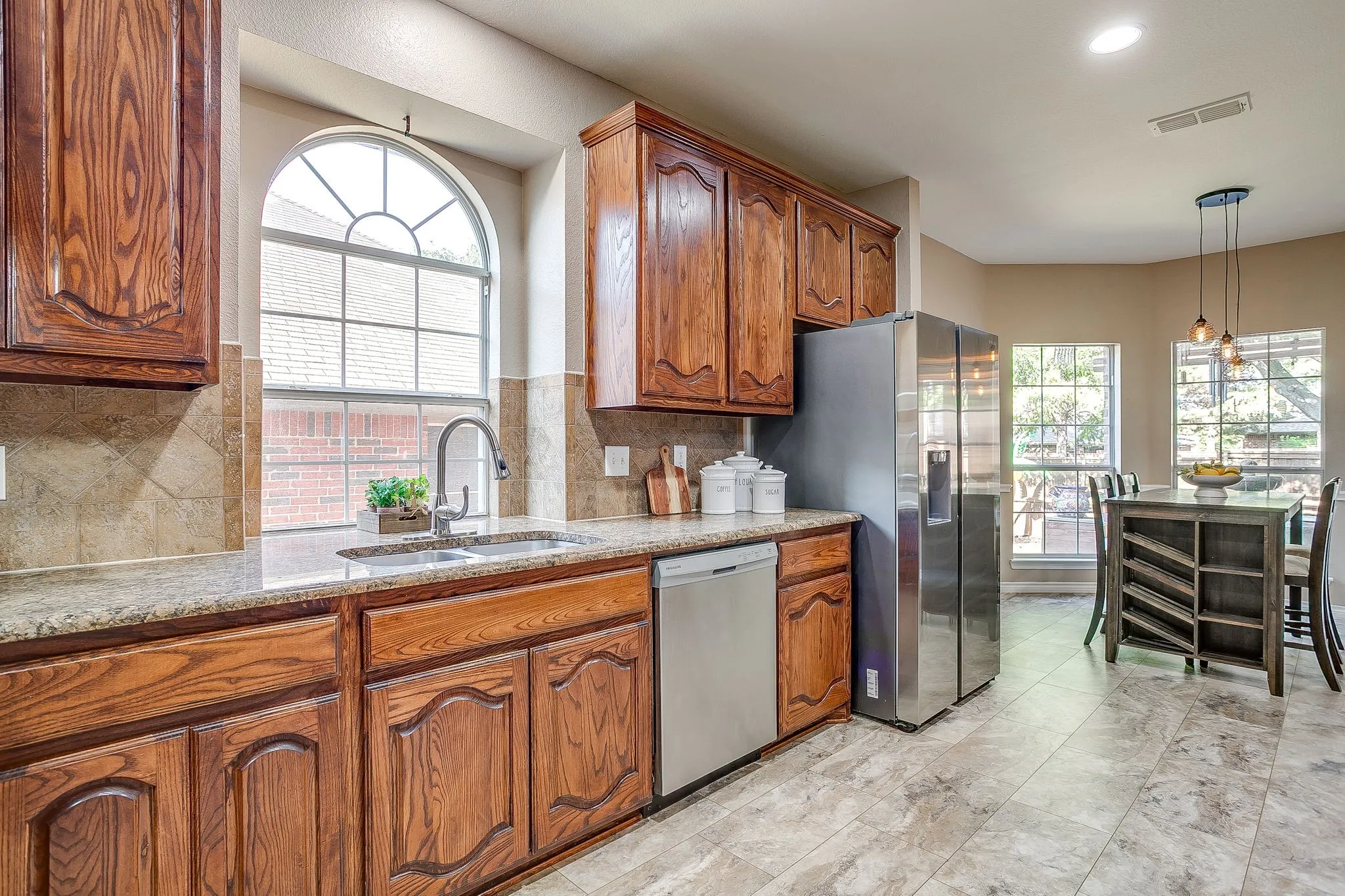 Kitchen featuring rich wood cabinetry, stone countertops, stainless steel appliances, and a tiled backsplash