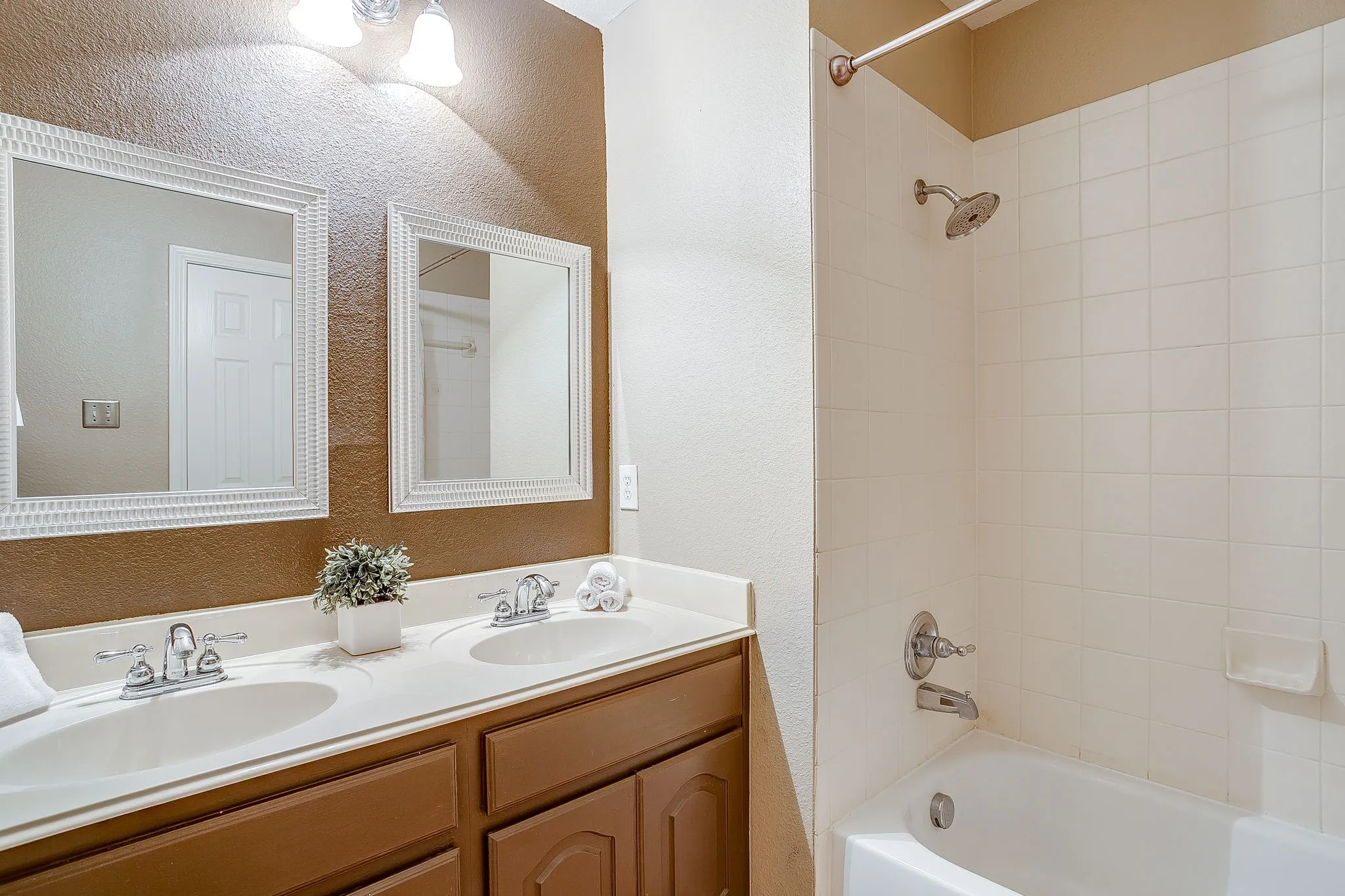 Dual vanity with white countertop and integrated sinks, brushed nickel faucets, and coordinating framed mirrors