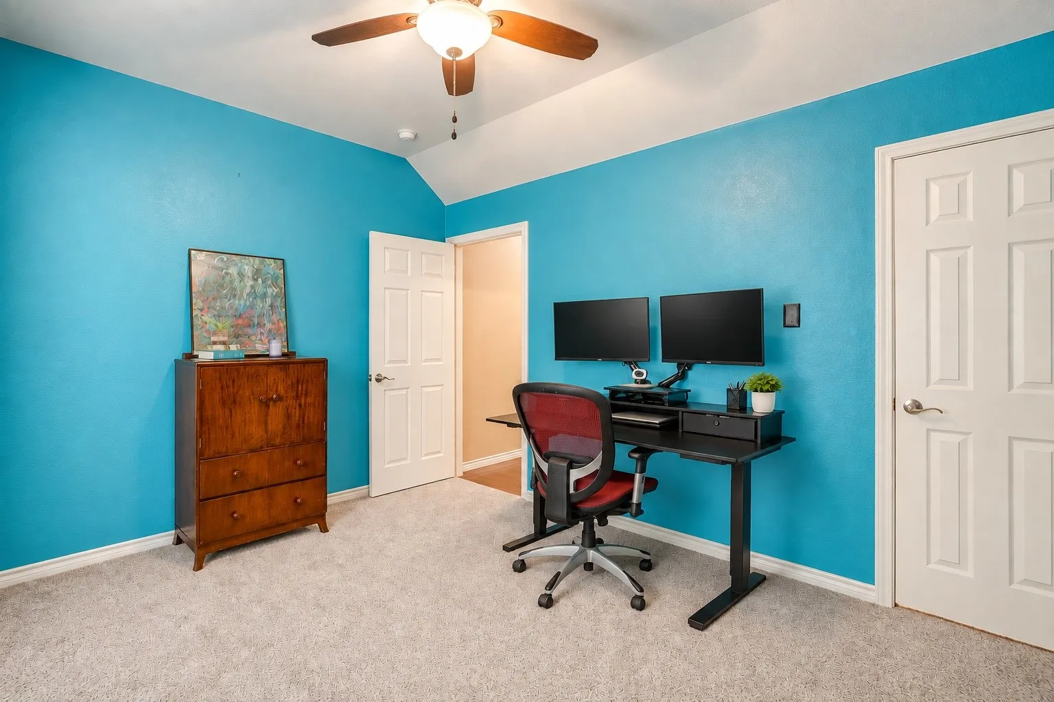 Vaulted ceiling with a ceiling fan, light-toned carpeting, and a paneled interior door