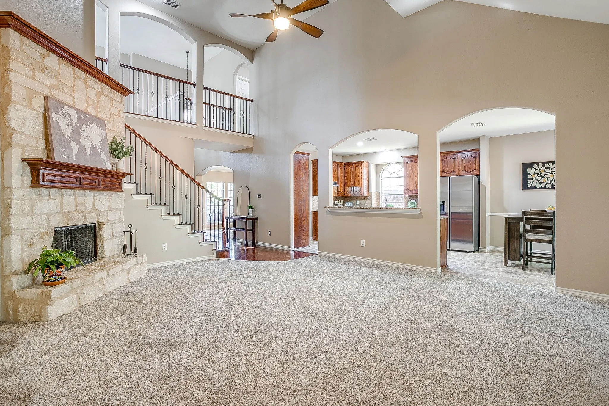 Two-story living area with a stone fireplace, vaulted ceiling, and an open balcony overlooking the space