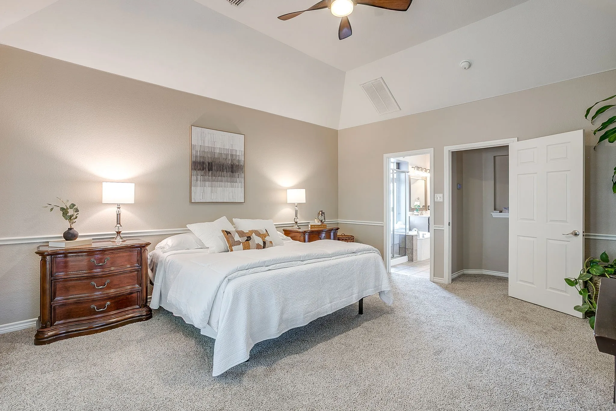 Vaulted ceiling with ceiling fan, light-toned carpeting, chair rail molding, and panel doors