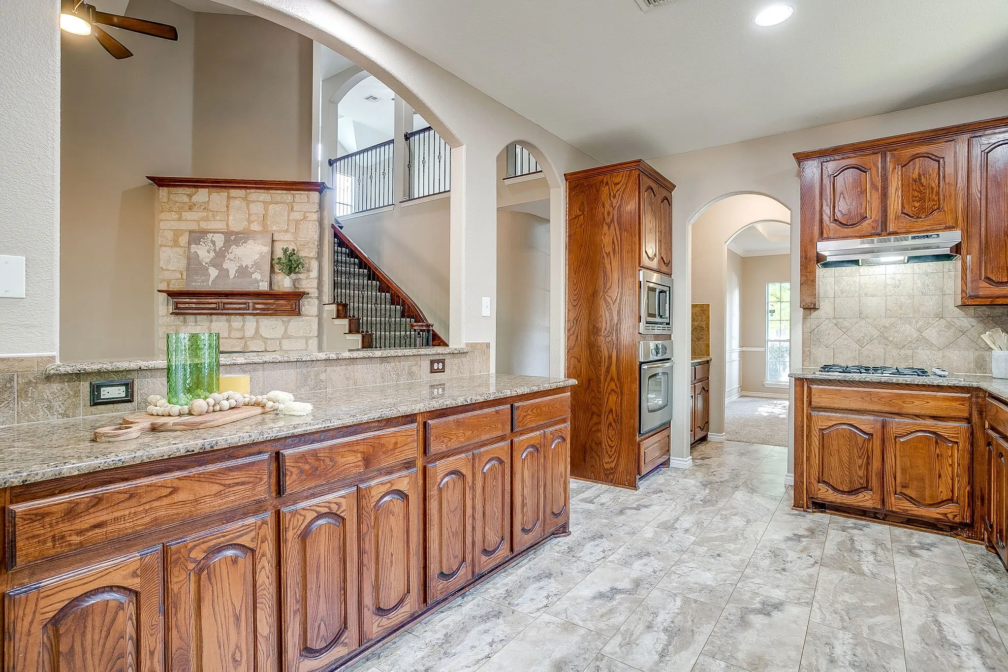 Kitchen featuring wood cabinetry, granite countertops, tile flooring, and integrated wall oven and microwave