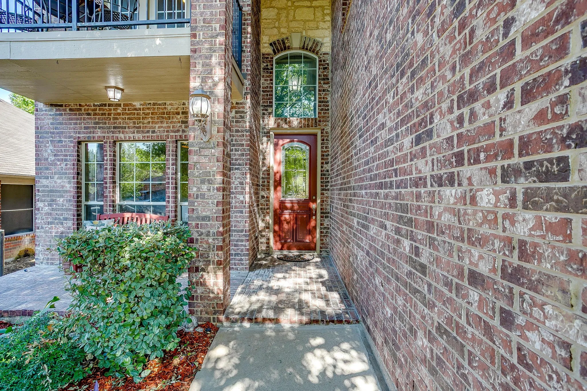 Brick exterior with stone accents, arched transom window, and a red front door