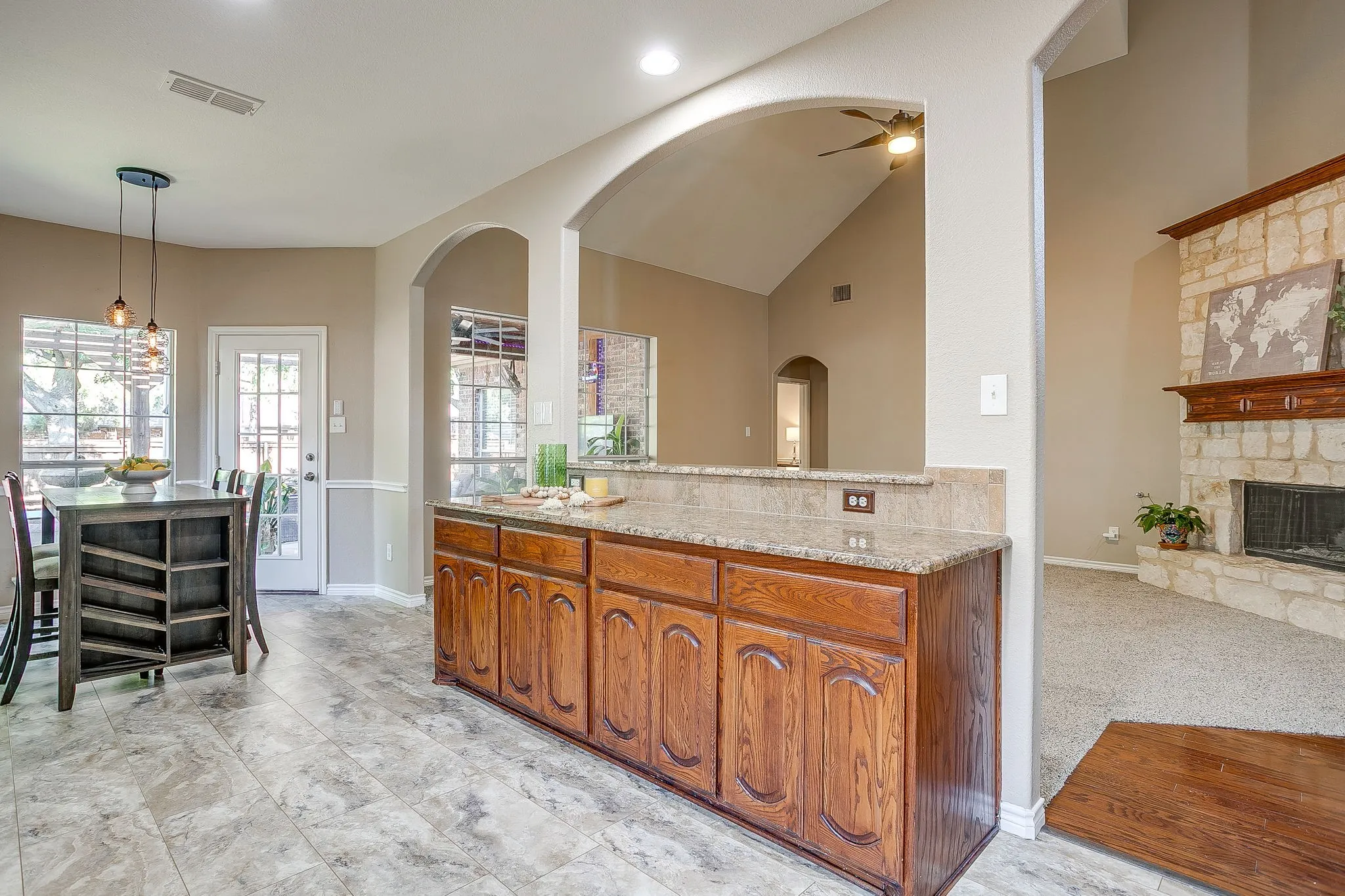 Wood-finish flooring, built-in cabinetry with granite-style countertop, and arched entryways