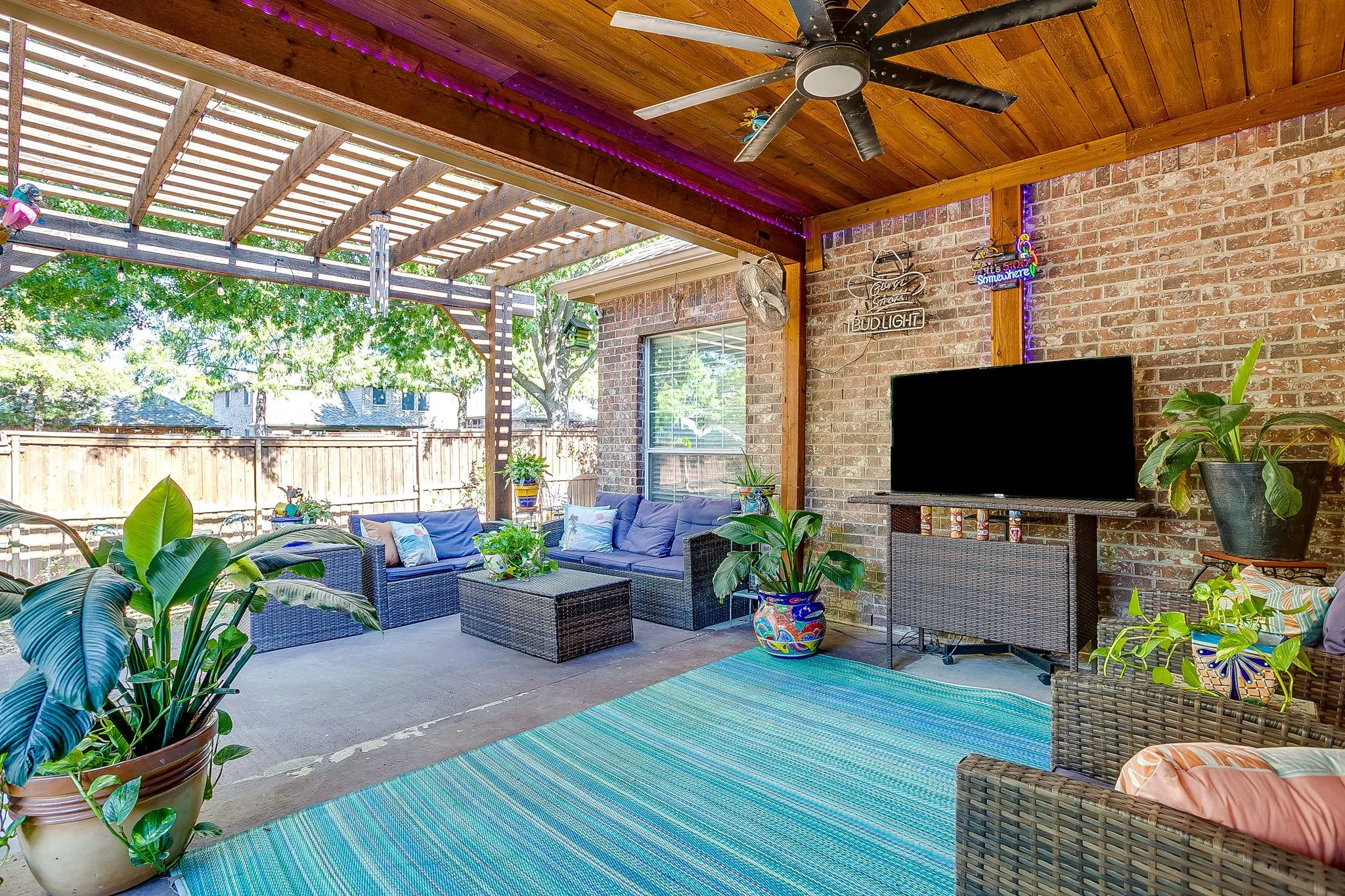 Covered patio with a wood-finish ceiling, exposed brick wall, and a wood pergola