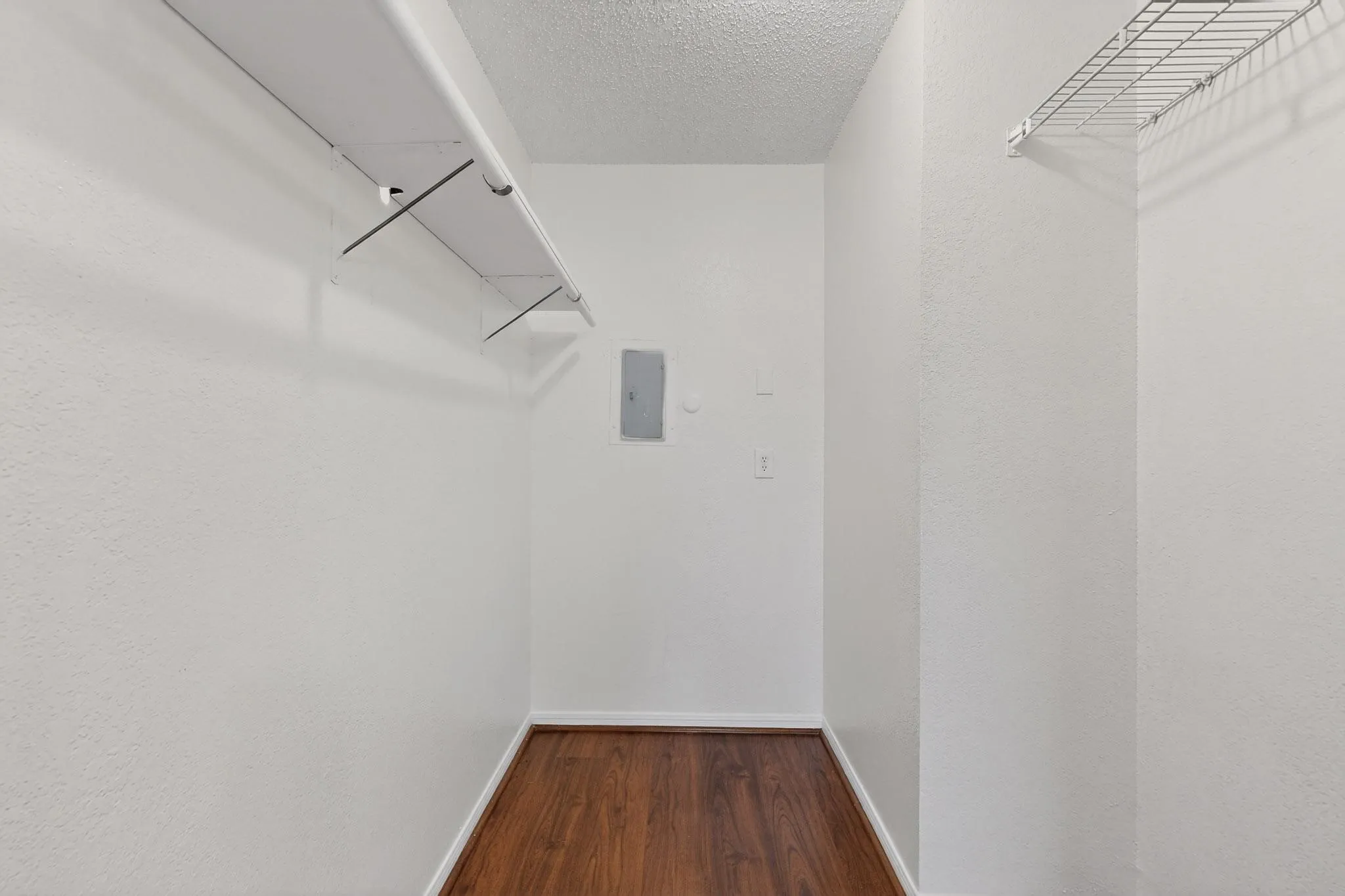 Walk in closet with dark wood-type flooring