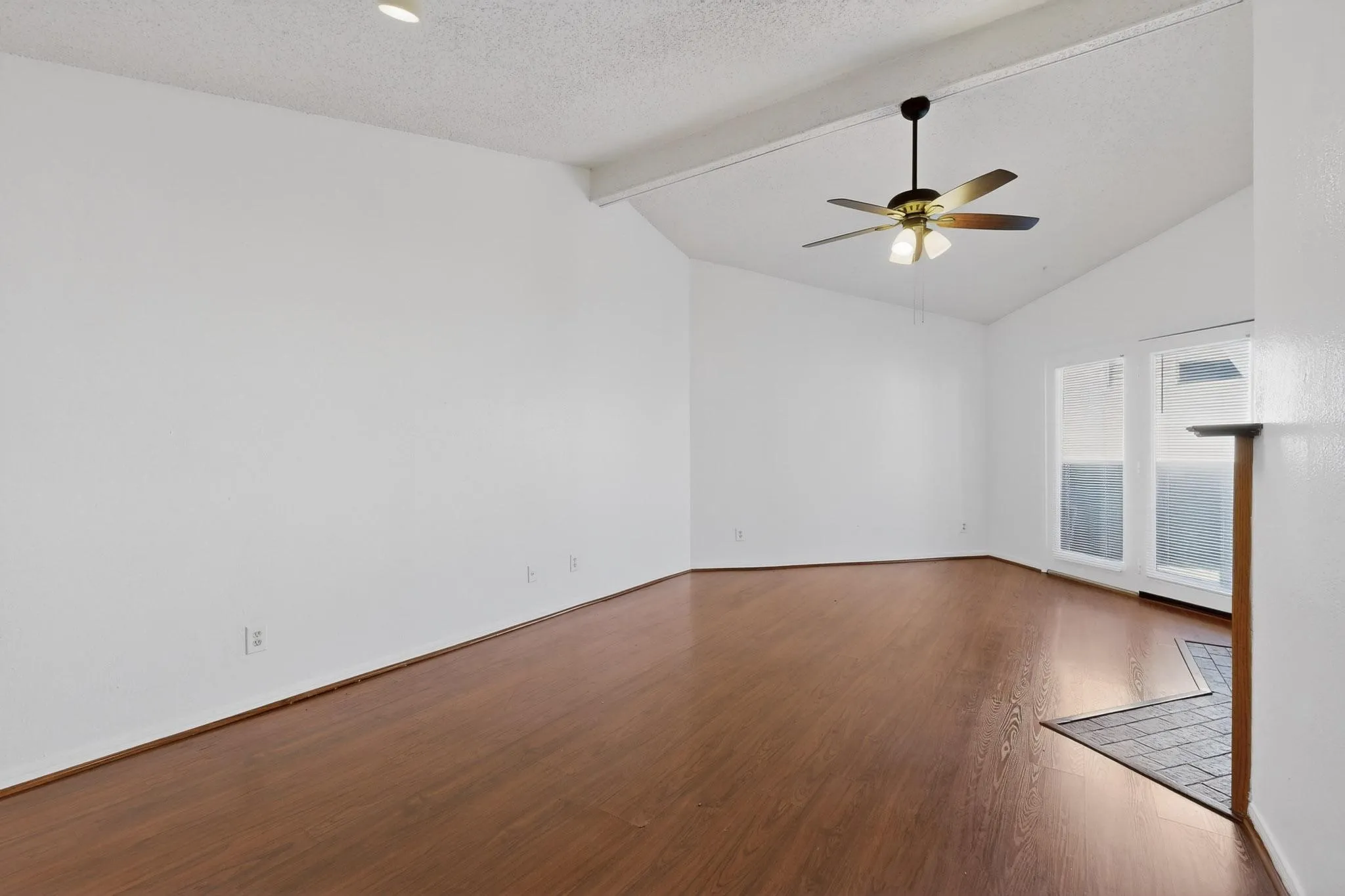 Spare room with beamed ceiling, dark wood-type flooring, a ceiling fan, and a textured ceiling
