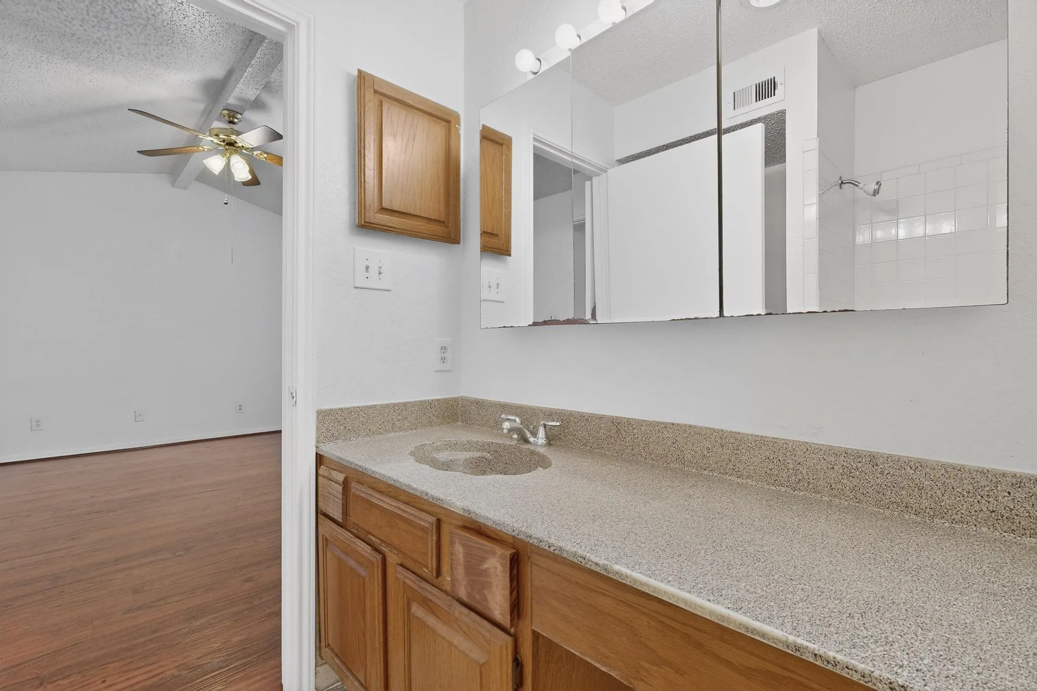 Full bathroom with a textured ceiling, vanity, wood finished floors, and a ceiling fan