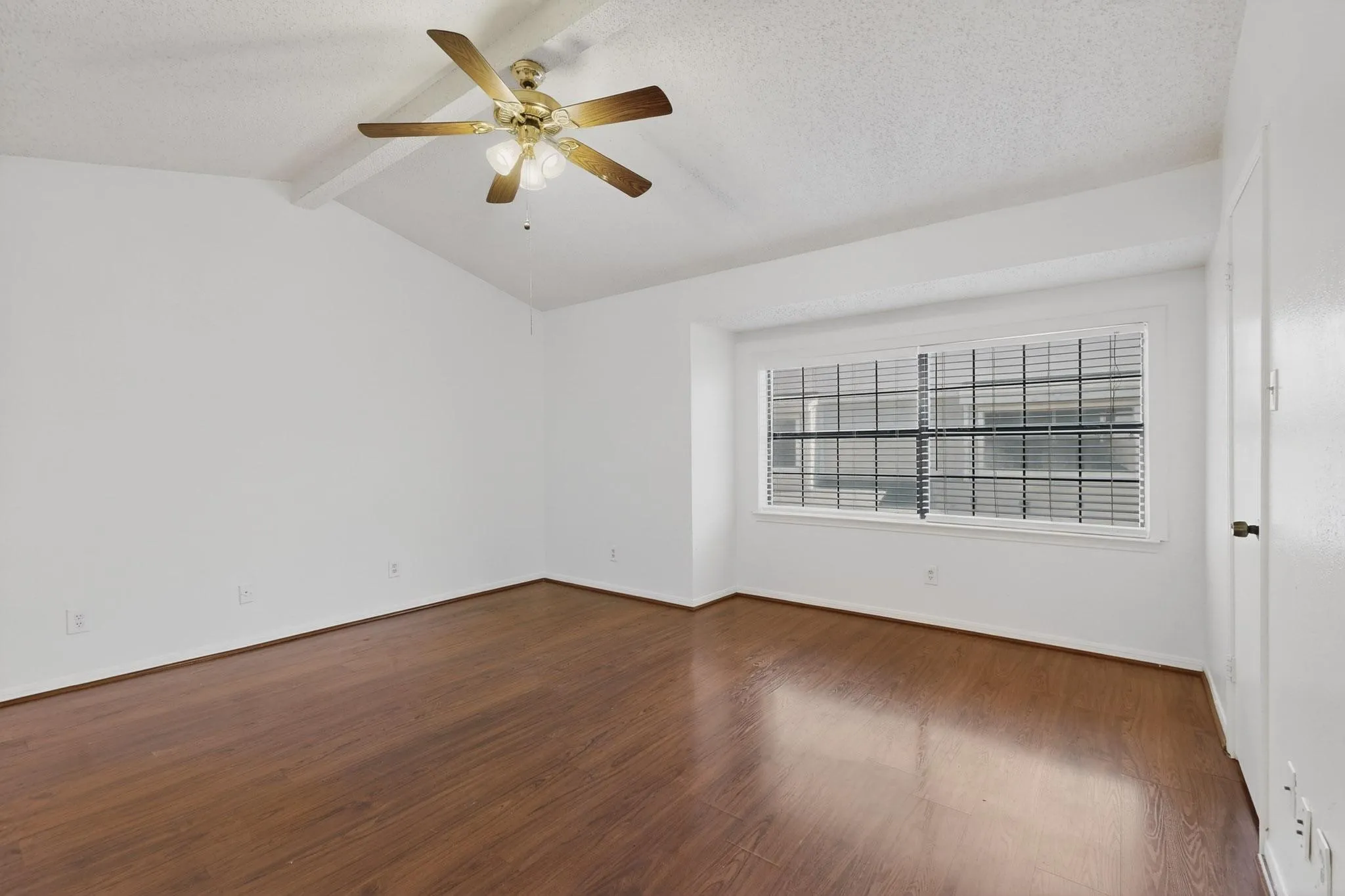 Spare room with a textured ceiling, beam ceiling, ceiling fan, and dark wood-style flooring