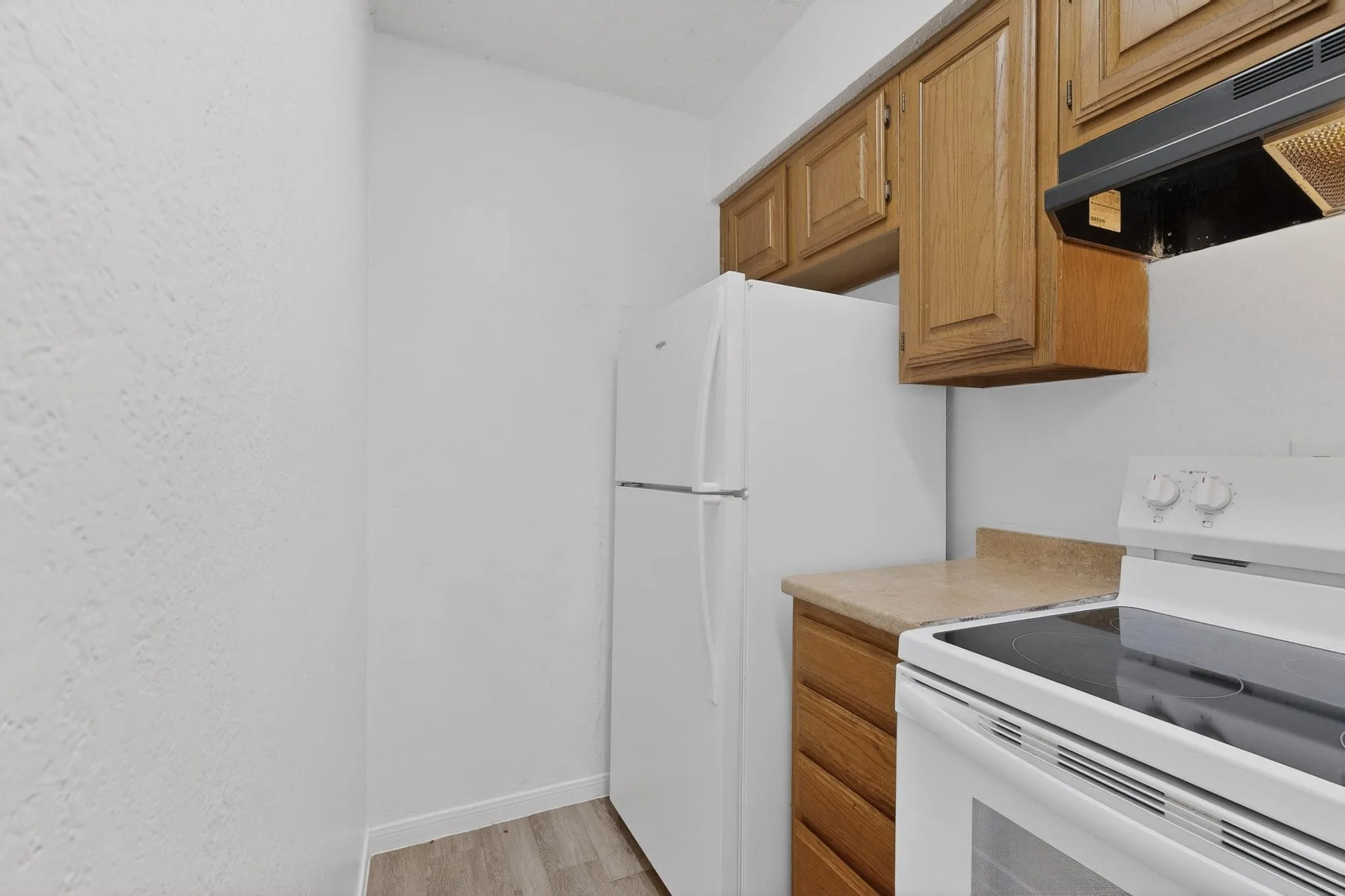 Kitchen featuring electric range, extractor fan, light countertops, light wood-style floors, and wood finish cabinetry