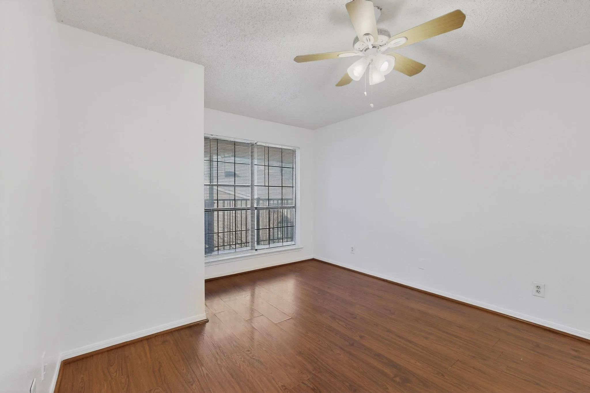Spare room with dark wood finished floors, a ceiling fan, and a textured ceiling