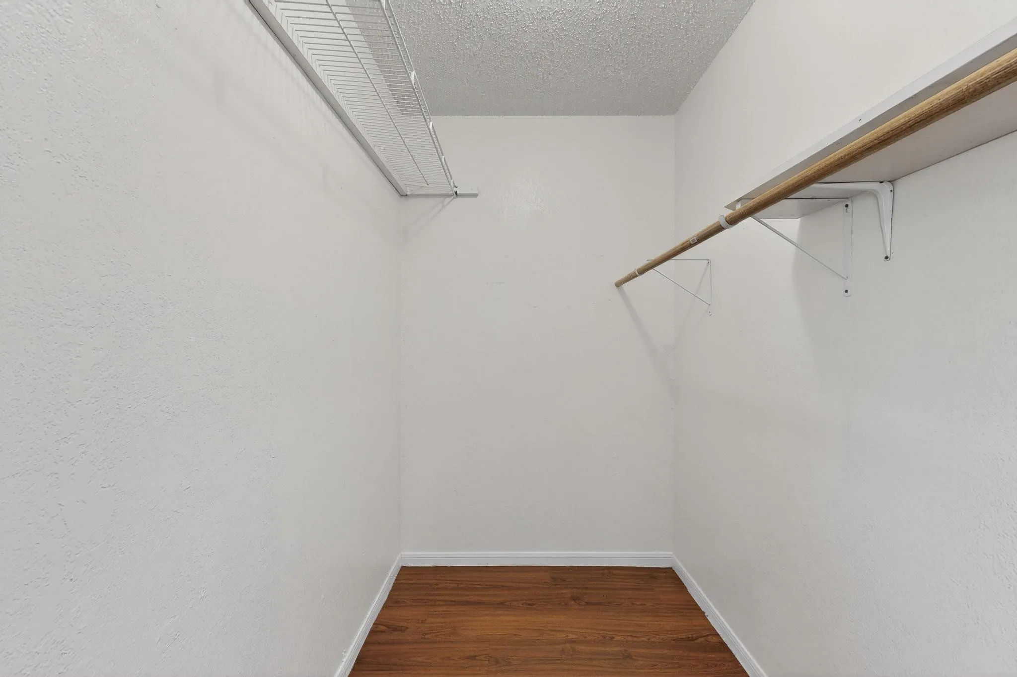 Walk in closet with dark wood-style floors