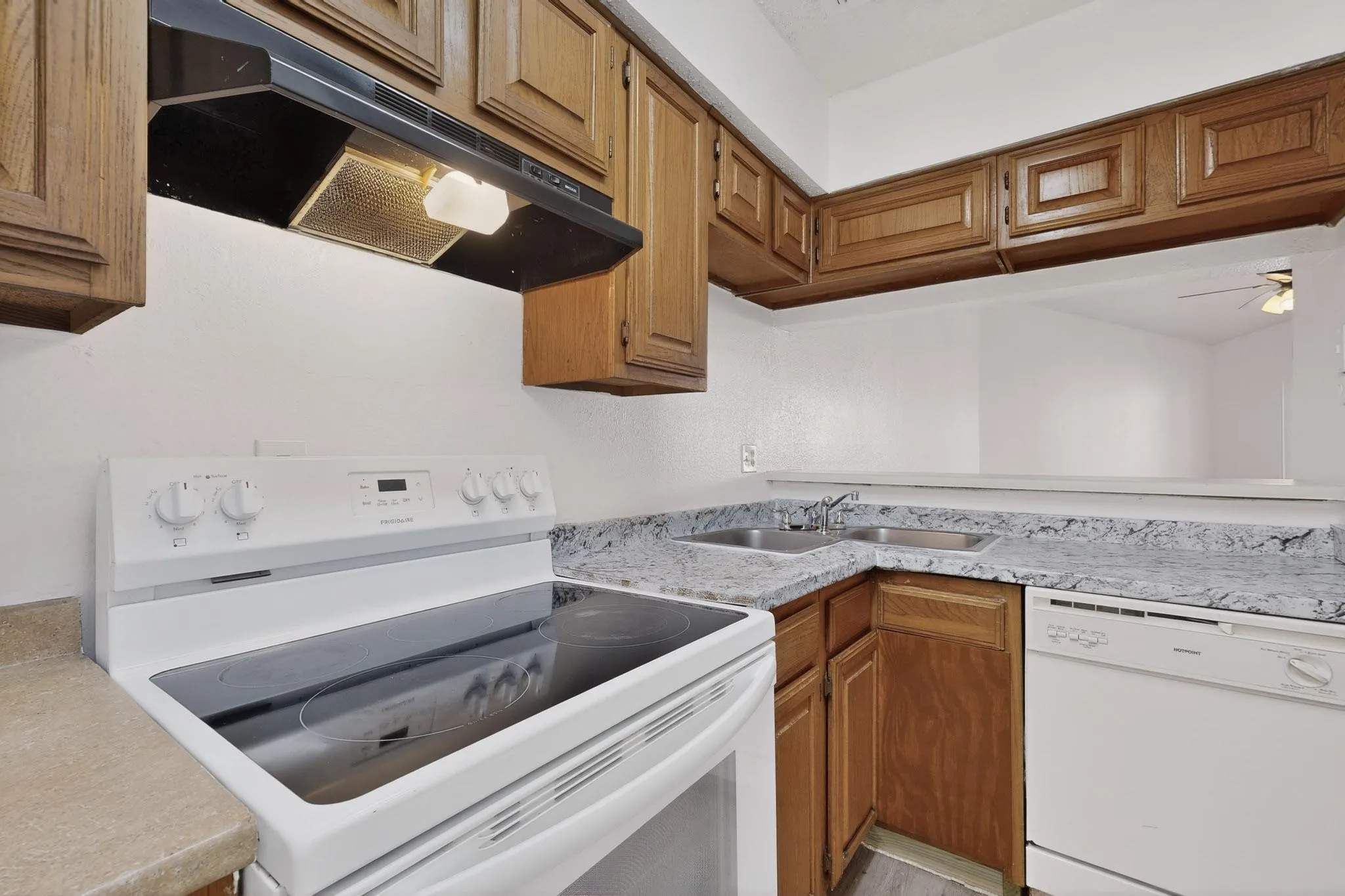 Kitchen featuring white appliances, light countertops, wood finish cabinets, and ceiling fan