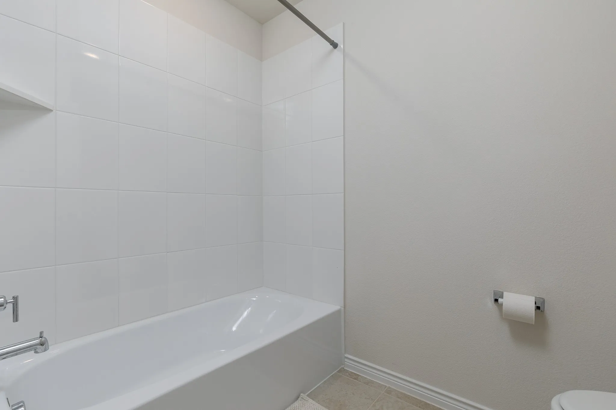Bathtub with white tile surround and chrome fixtures