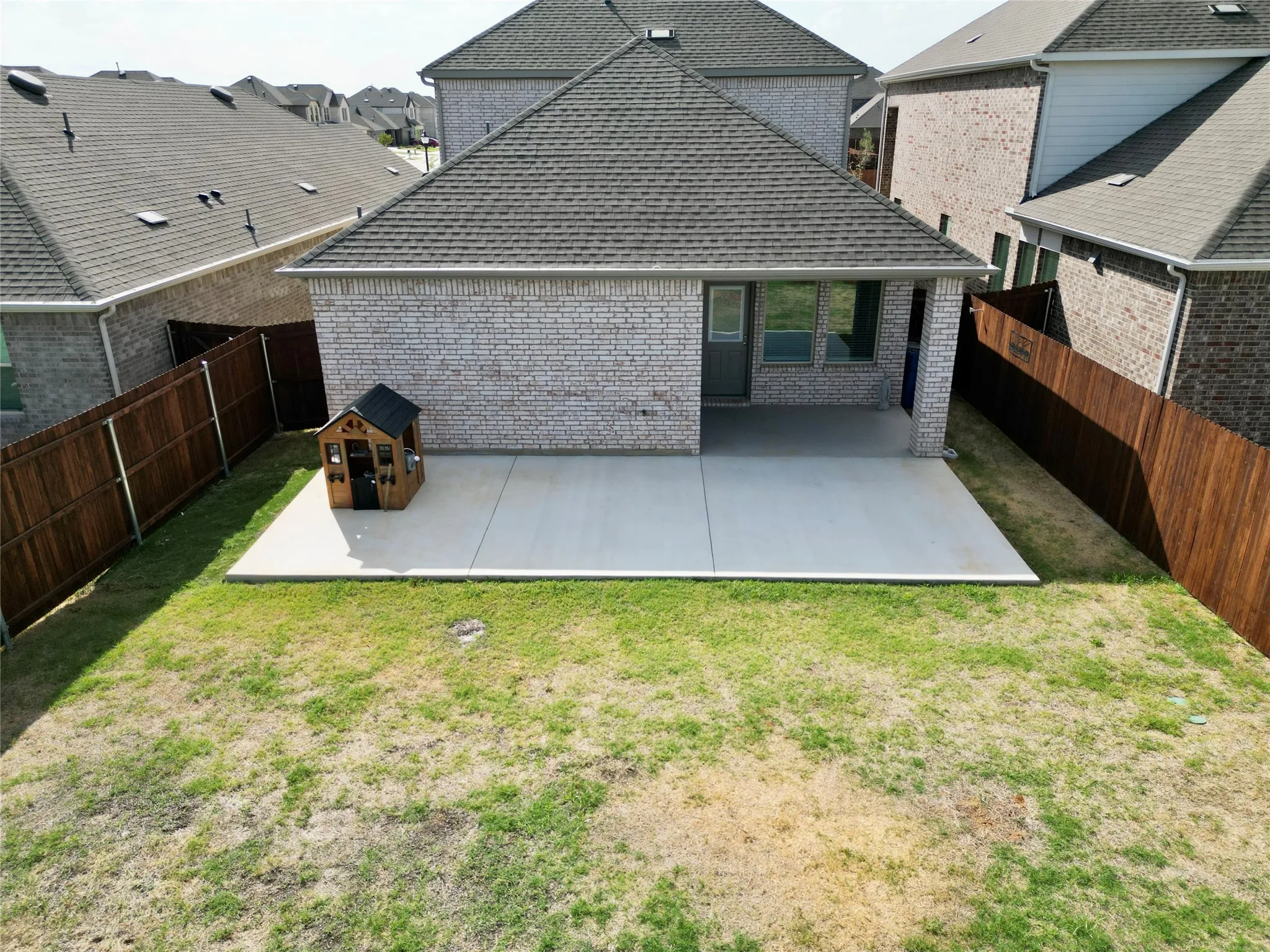 Expansive backyard featuring a covered patio, additional concrete patio, and privacy fencing