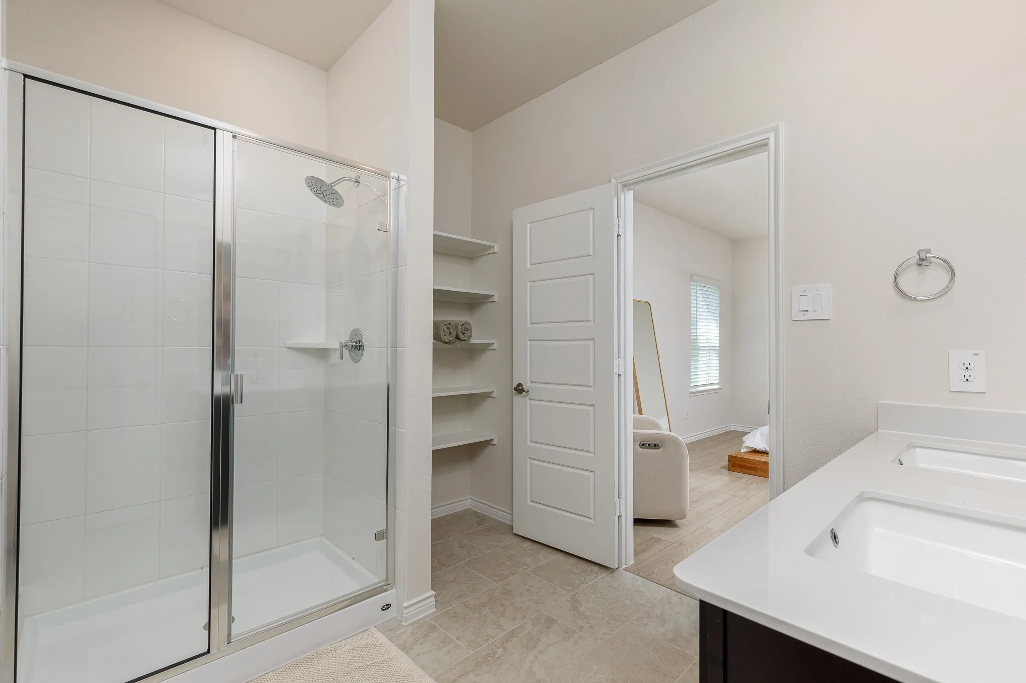 Glass-enclosed shower with white tiled walls and a built-in shelf