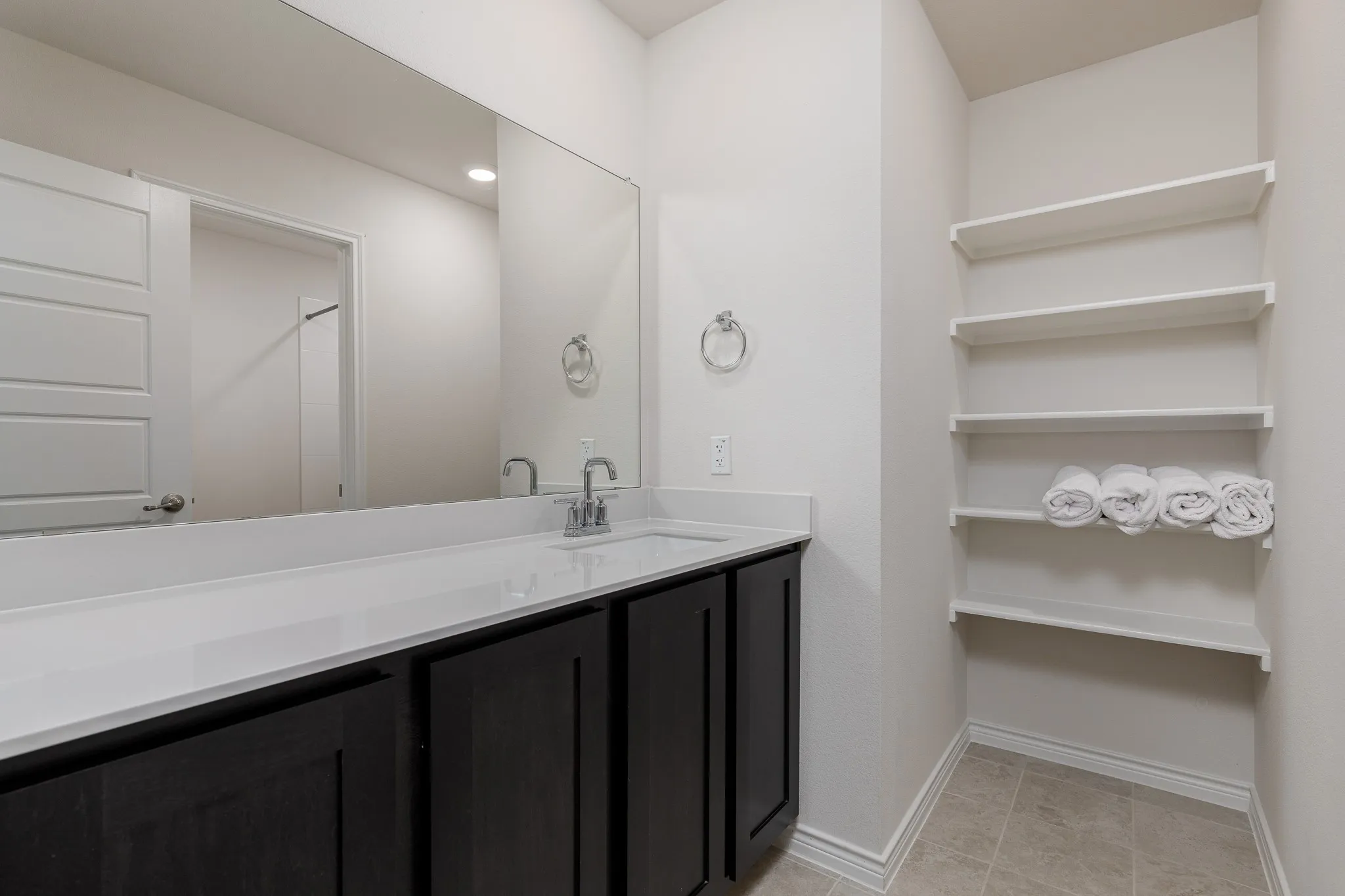 Vanity with dark cabinetry and a white countertop, featuring a single sink and chrome faucet