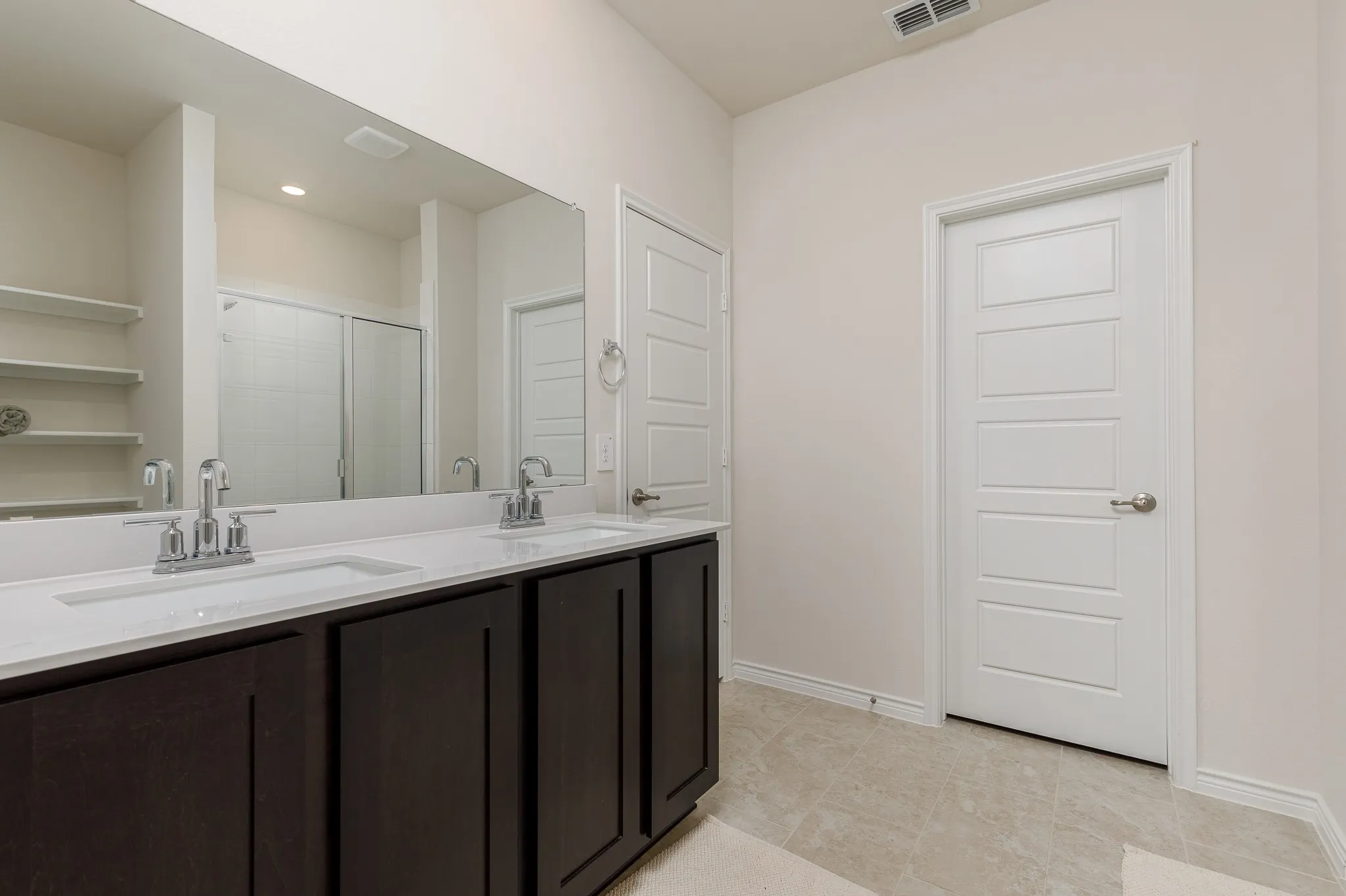 Double vanity with undermount sinks, chrome fixtures, and dark wood-finish cabinetry