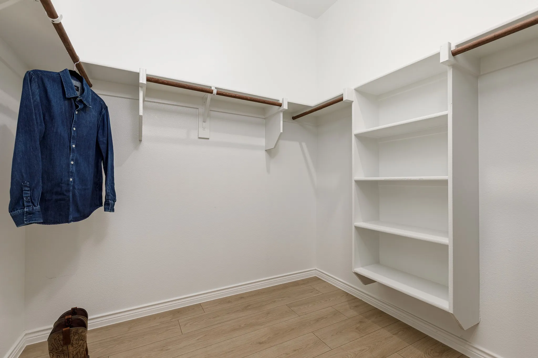 Built-in shelving, multiple hanging rods, and wood-finish flooring