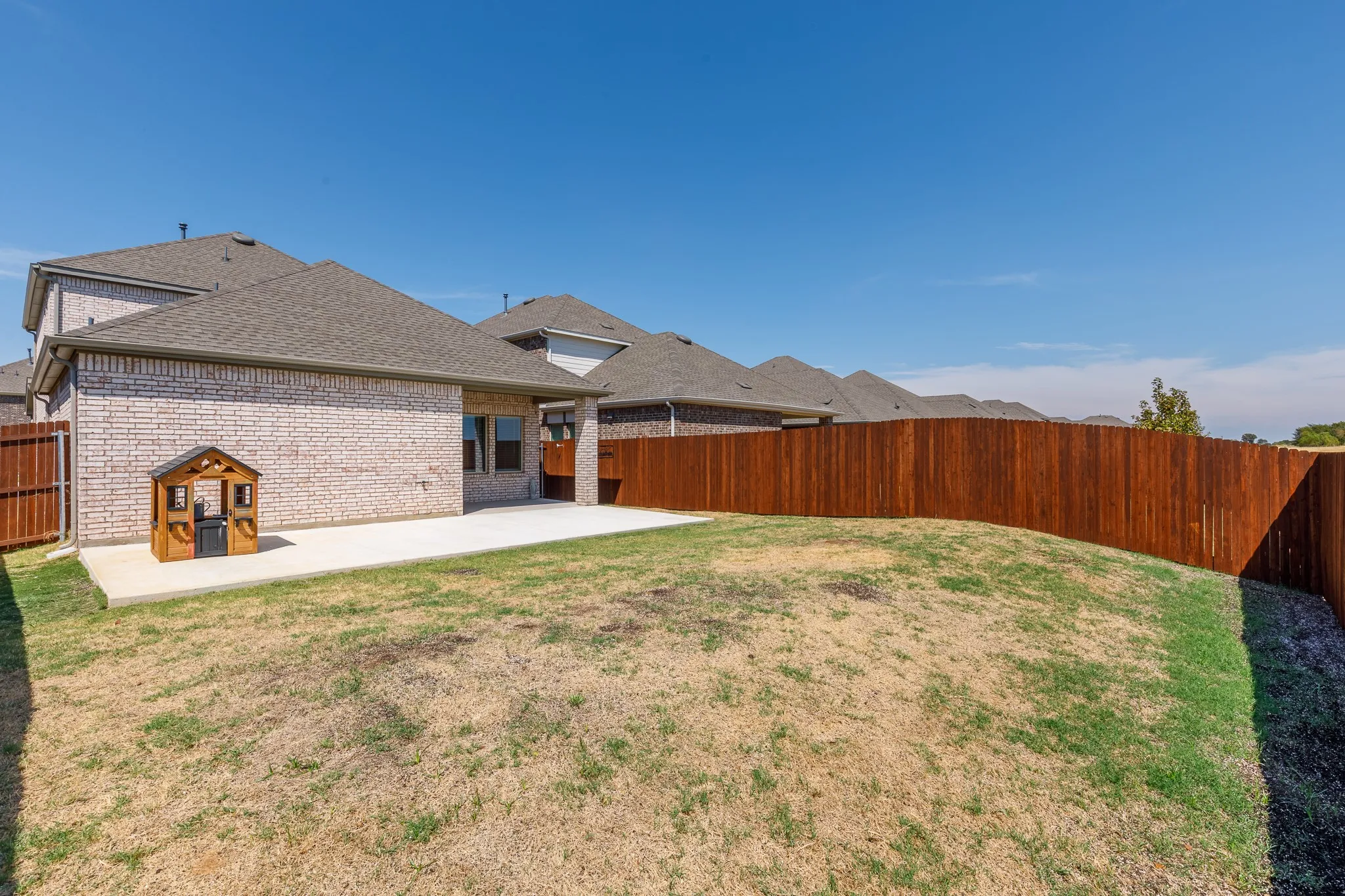 Exterior featuring brick siding, a concrete patio, and a wood privacy fence