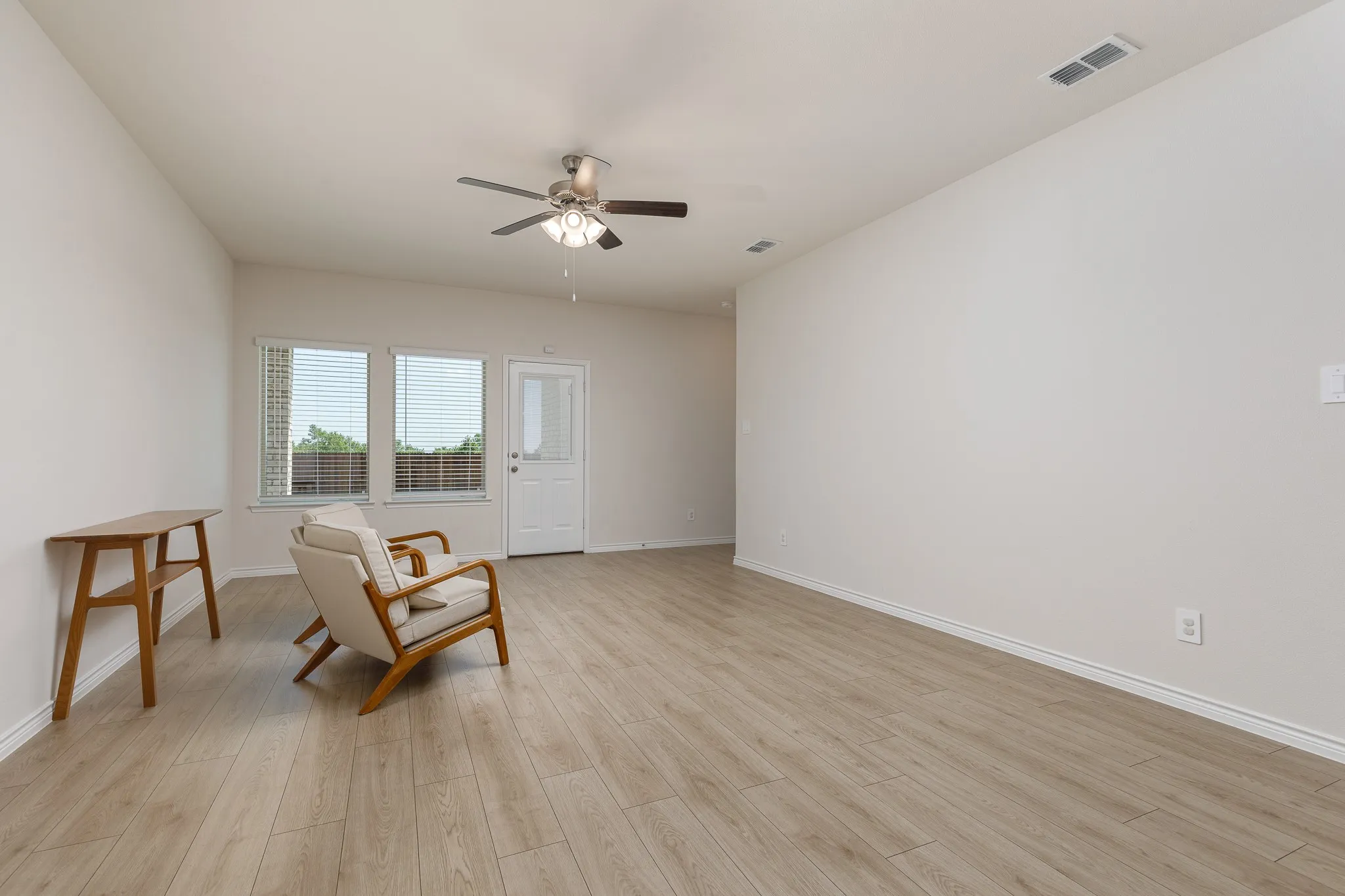 Wood-finish flooring, white walls, and a ceiling fan with integrated lighting