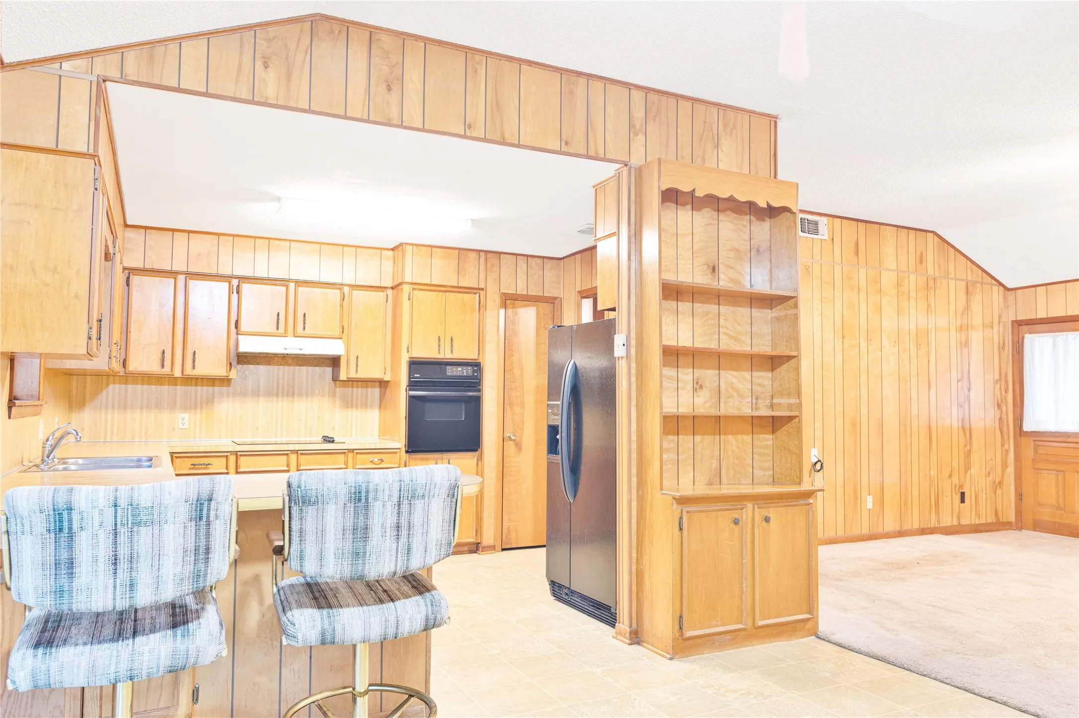 Kitchen featuring wood-paneled walls, built-in cabinetry, and a double basin sink