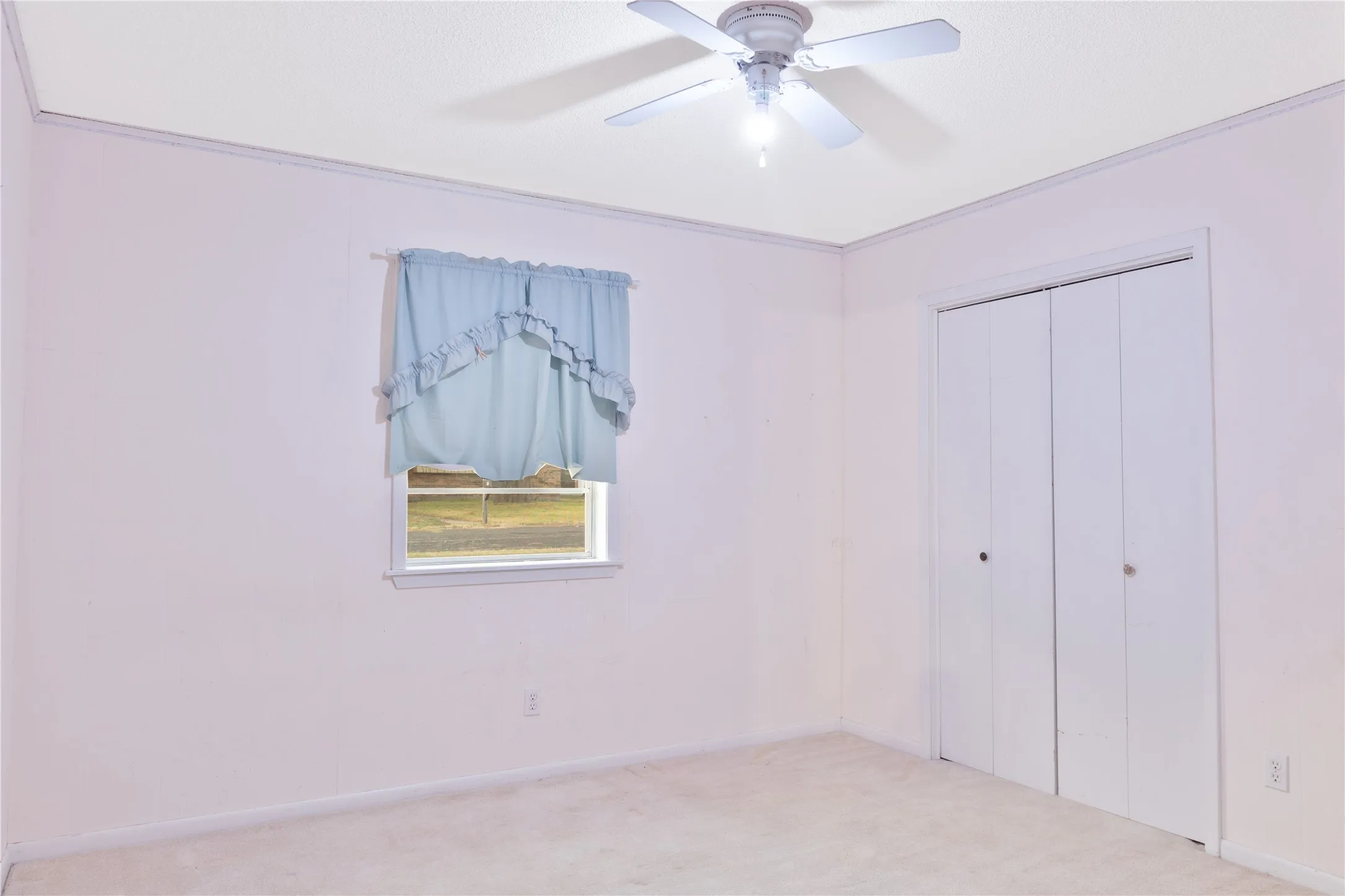 Ceiling fan with integrated lighting, window with trim, carpeted flooring, and bi-fold closet doors