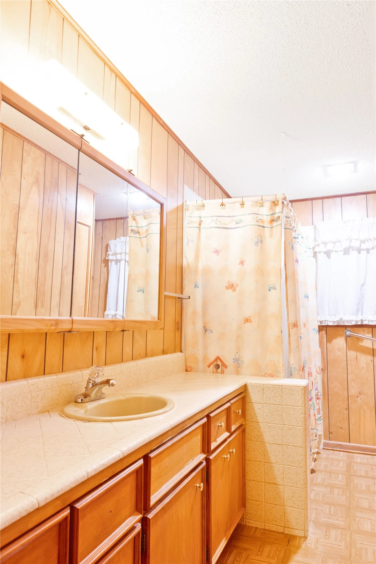 Wood paneling accents a bathroom vanity with integrated sink and storage cabinetry