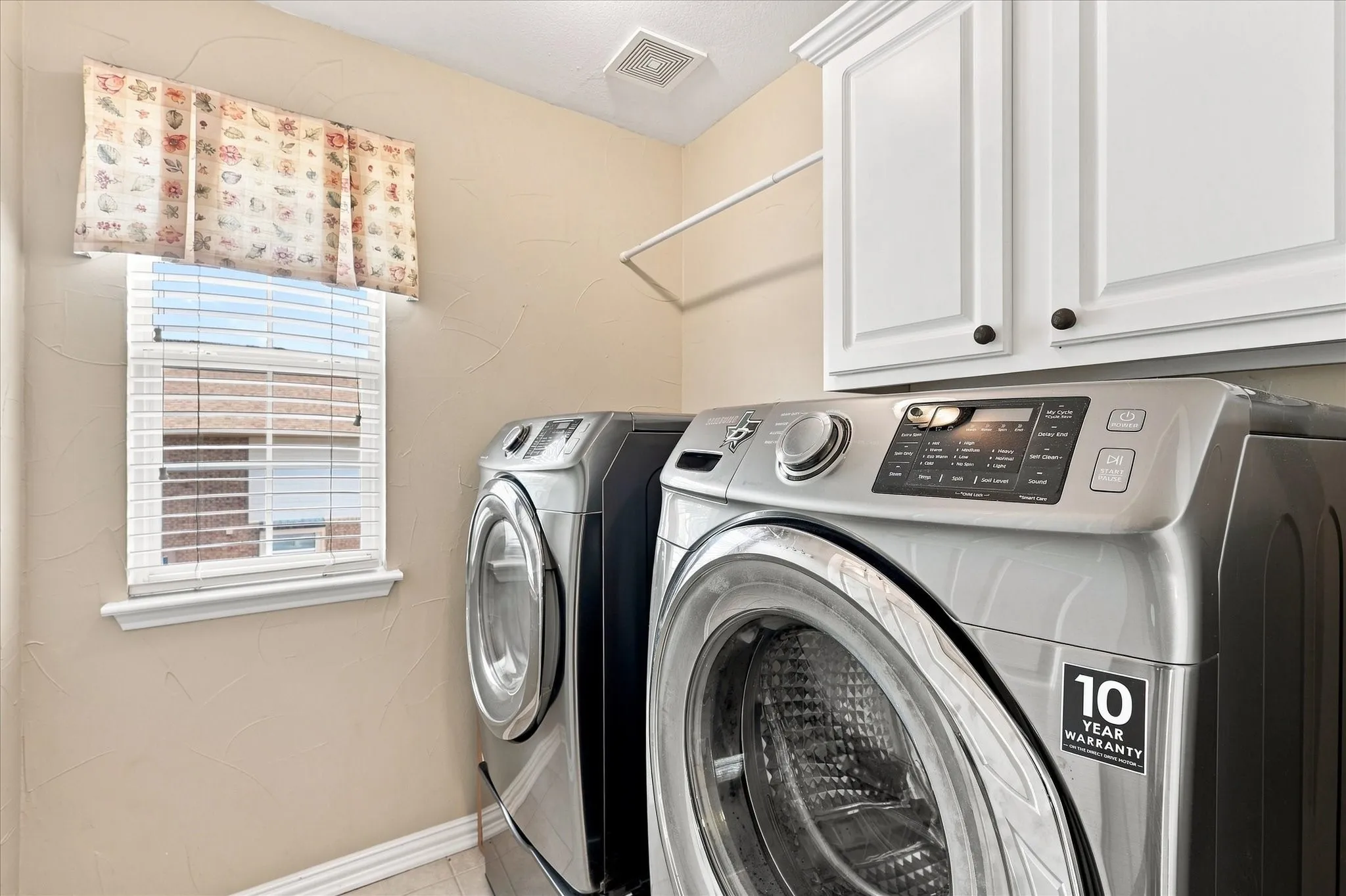 Laundry area featuring a window, built-in white cabinetry, and a storage shelf