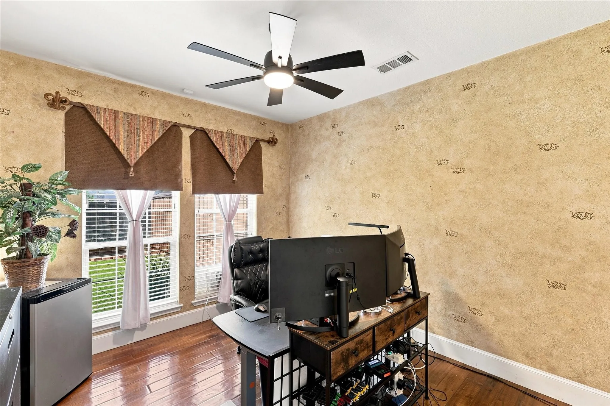 Hardwood-finish flooring, textured wall treatment, and a ceiling fan with integrated lighting