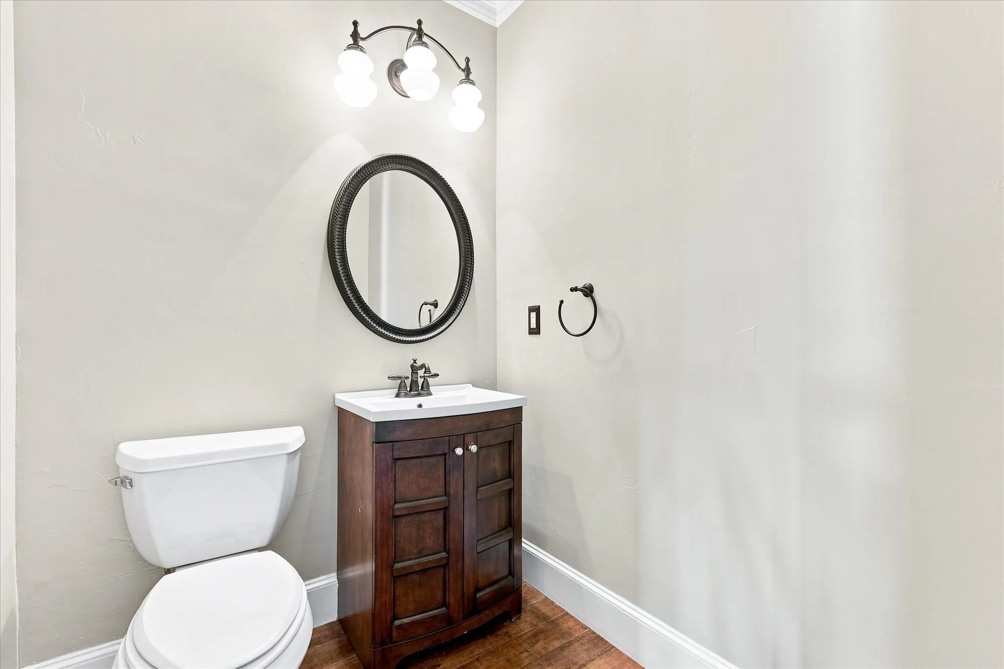 White toilet with a dark wood-finish vanity and white countertop