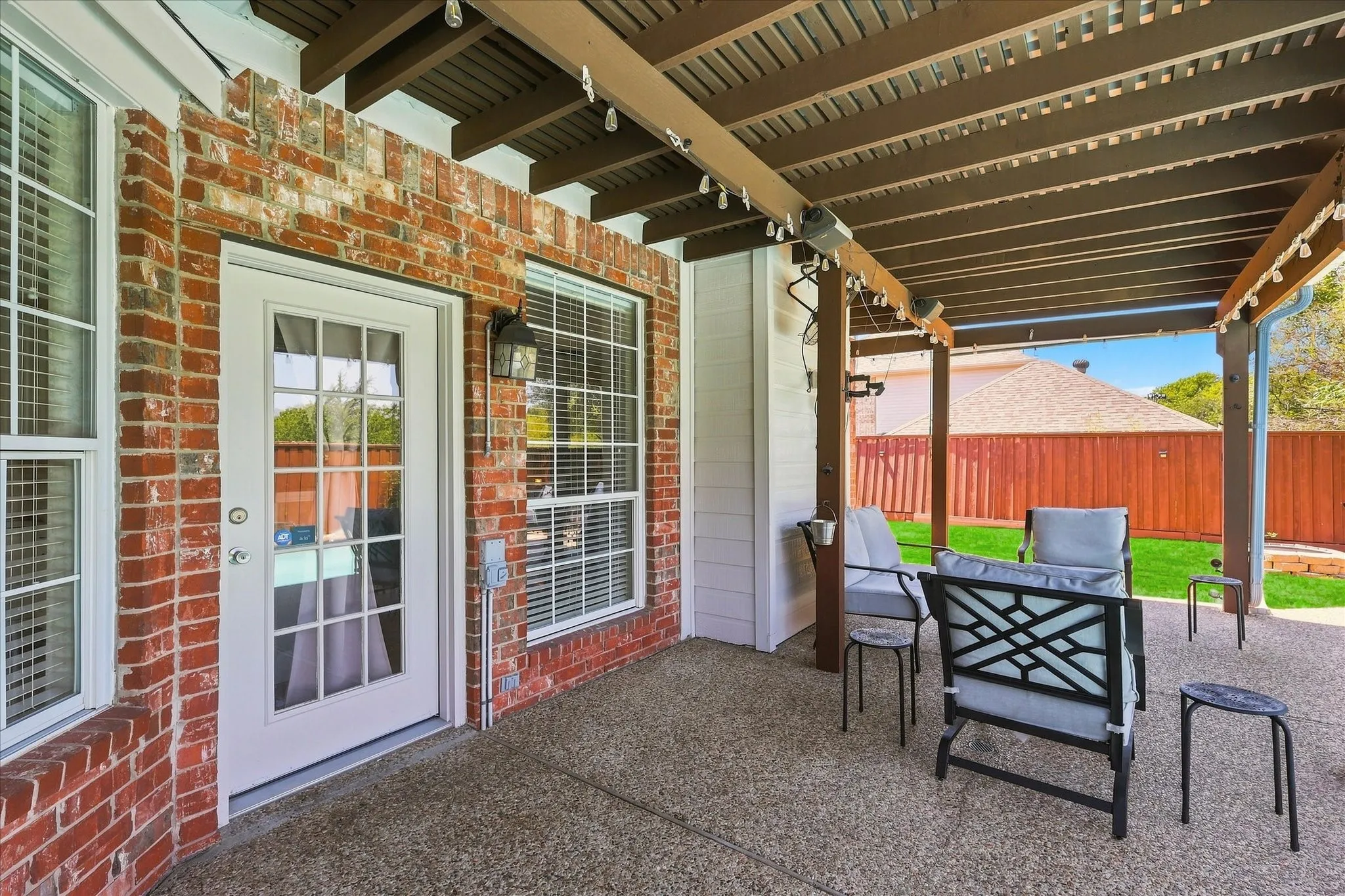 Covered patio with a slatted ceiling, exposed aggregate flooring, and brick exterior walls