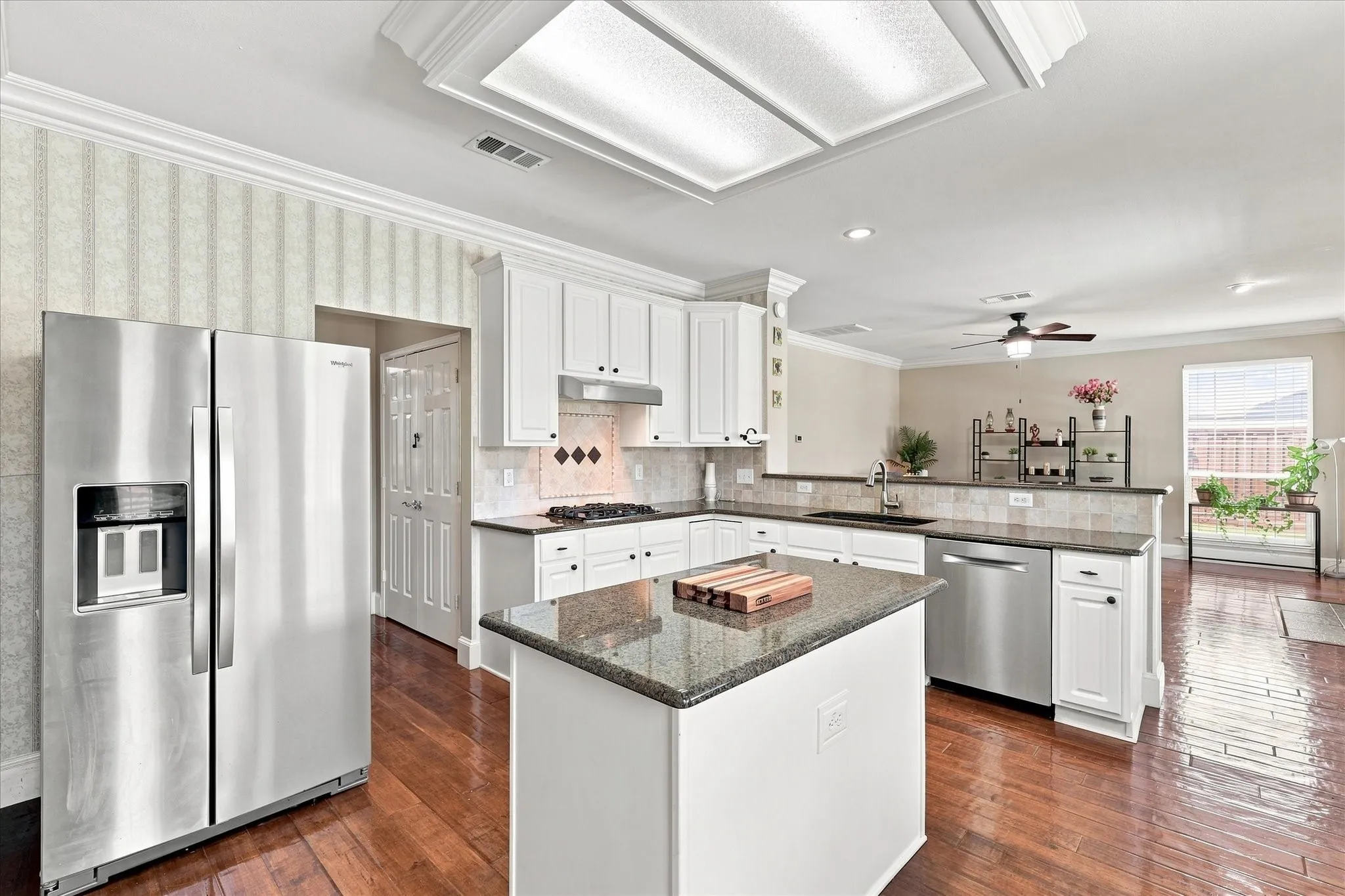 Kitchen featuring white cabinetry, a central island with a stone-finish countertop, stainless steel appliances, and wood-finish flooring