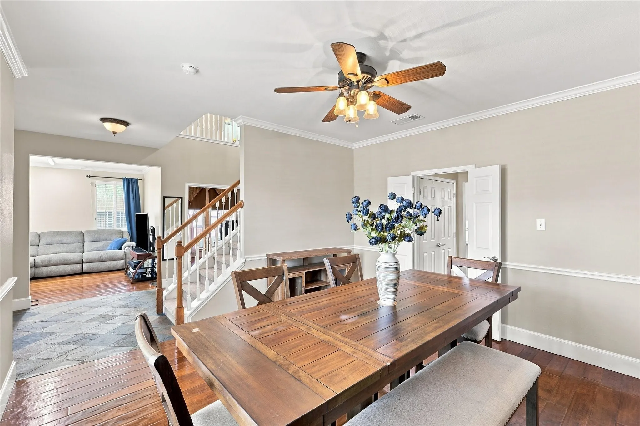 Hardwood flooring throughout, crown molding, chair rail molding, and a ceiling fan with integrated lighting