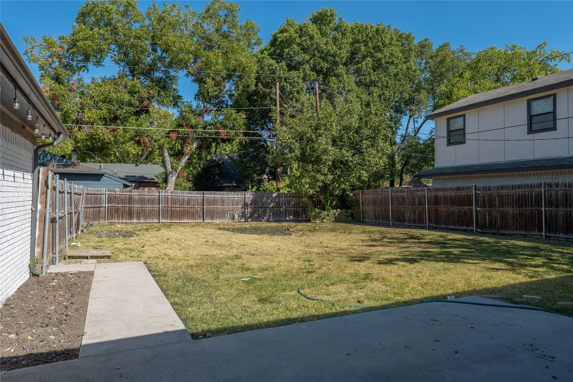 Expansive backyard featuring a concrete patio, a concrete walkway, and a full wood fence enclosure