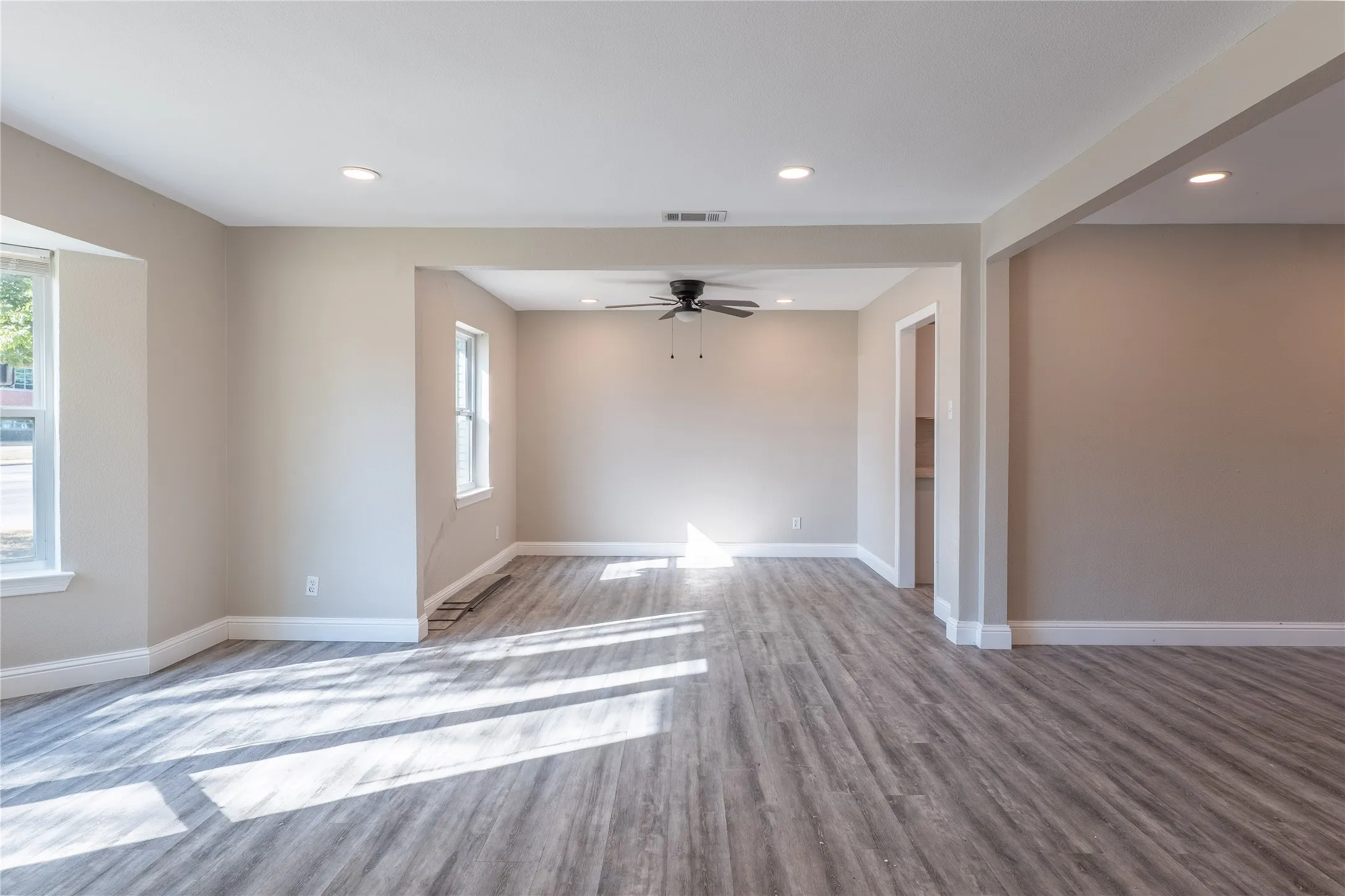 Spacious open-concept living area featuring wood-finish flooring, recessed lighting, and a ceiling fan