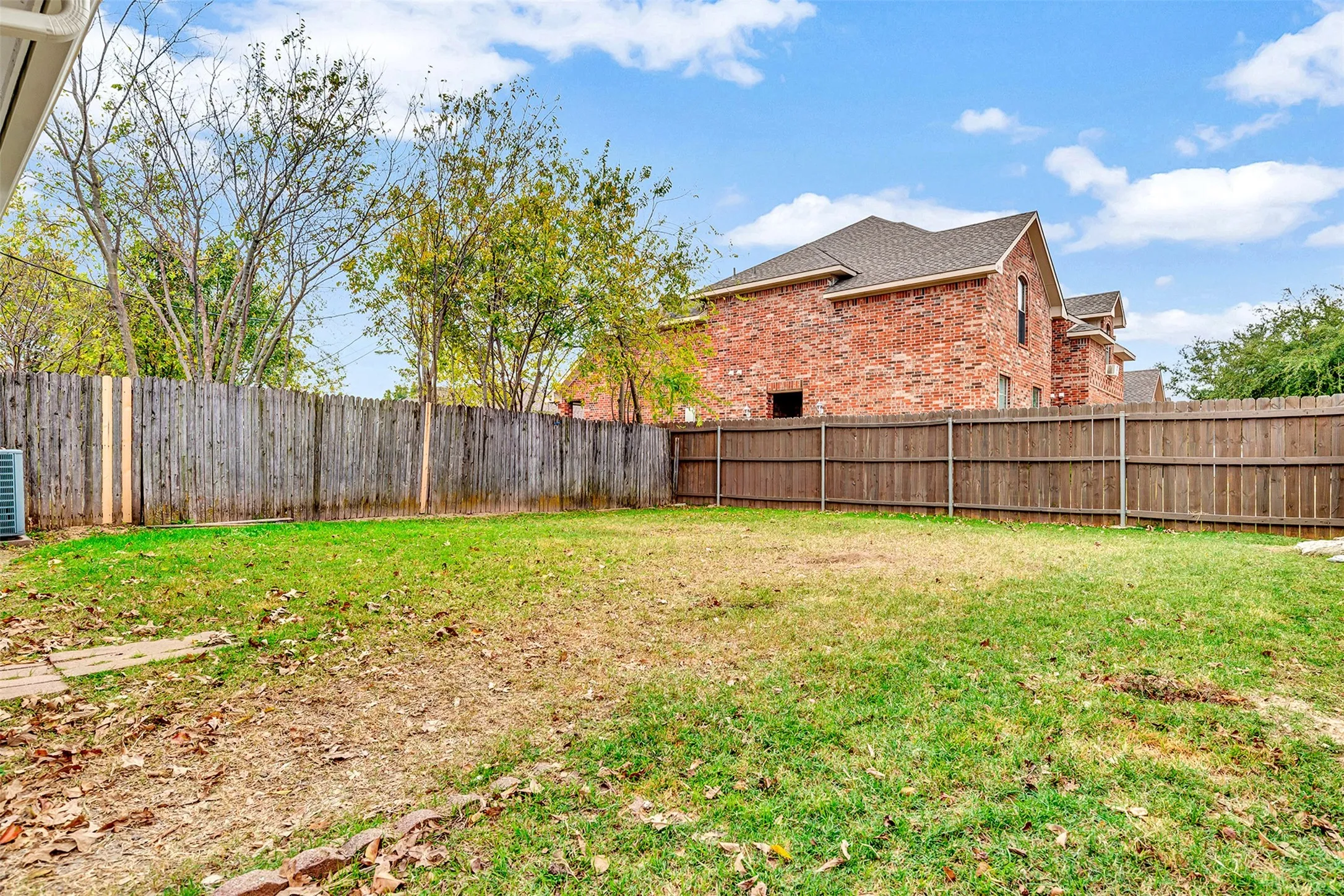 Spacious backyard featuring wood fencing and a visible brick exterior