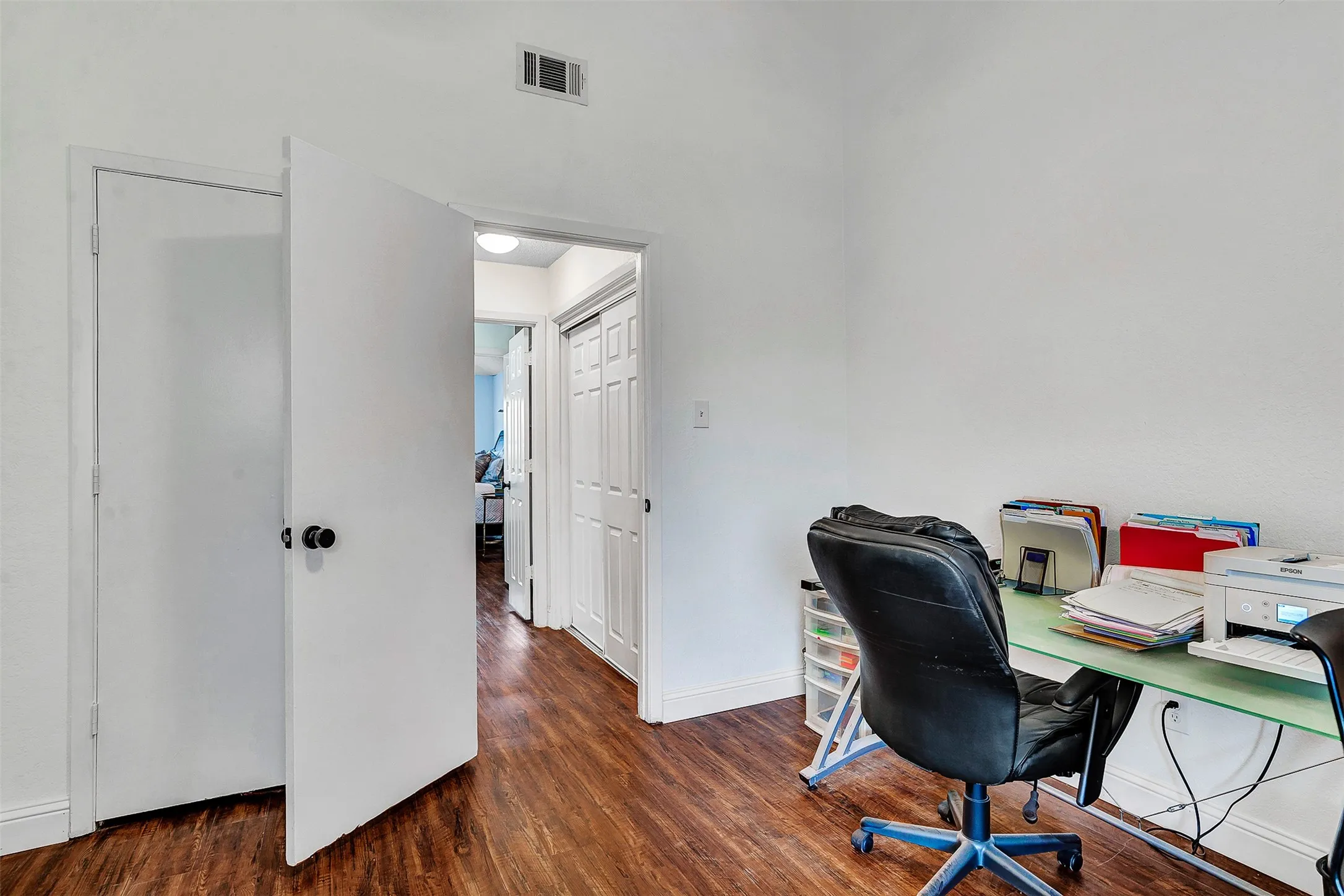 Wood-finish flooring throughout, bright white walls, and white interior doors with black hardware